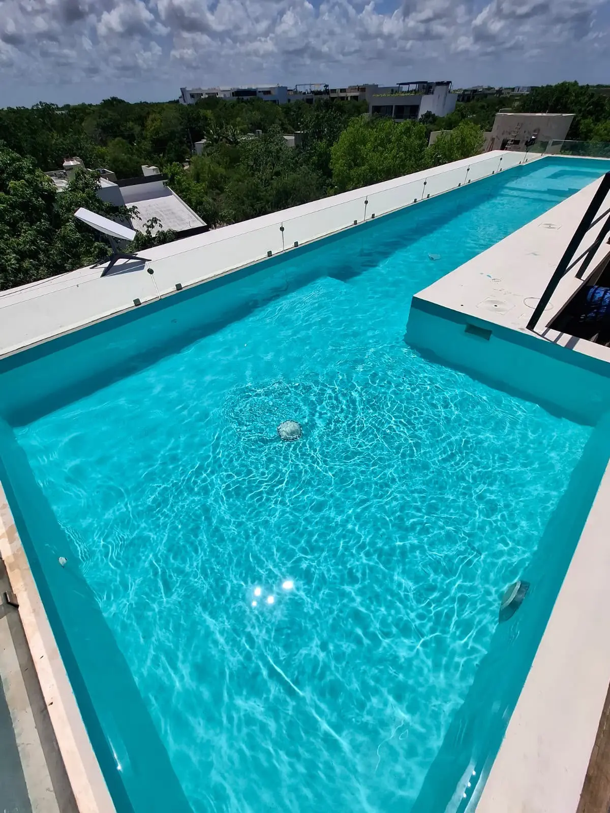 Rooftop rectangular turquoise swimming pool on sunny day