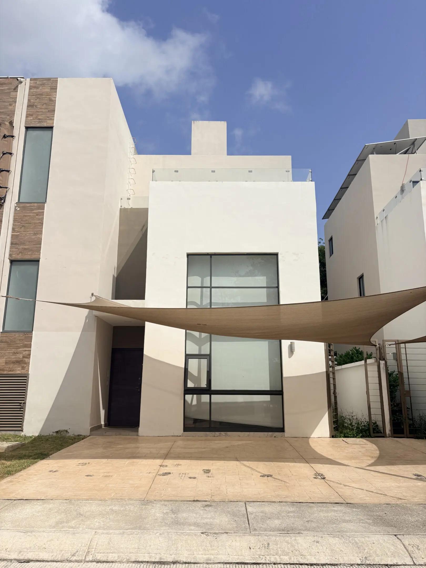 Modern white house with beige shade sail