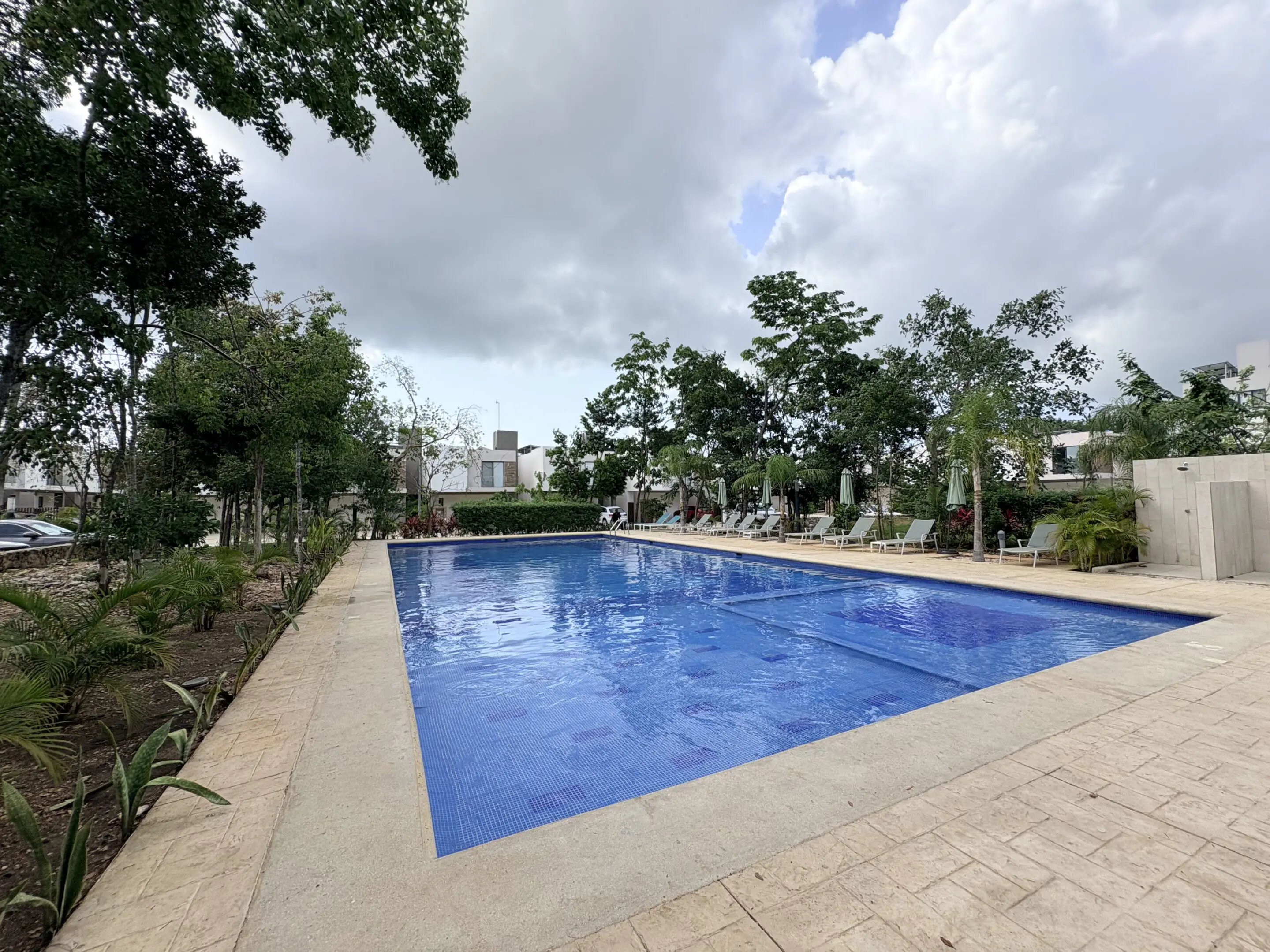 Outdoor rectangular blue swimming pool with lounge chairs