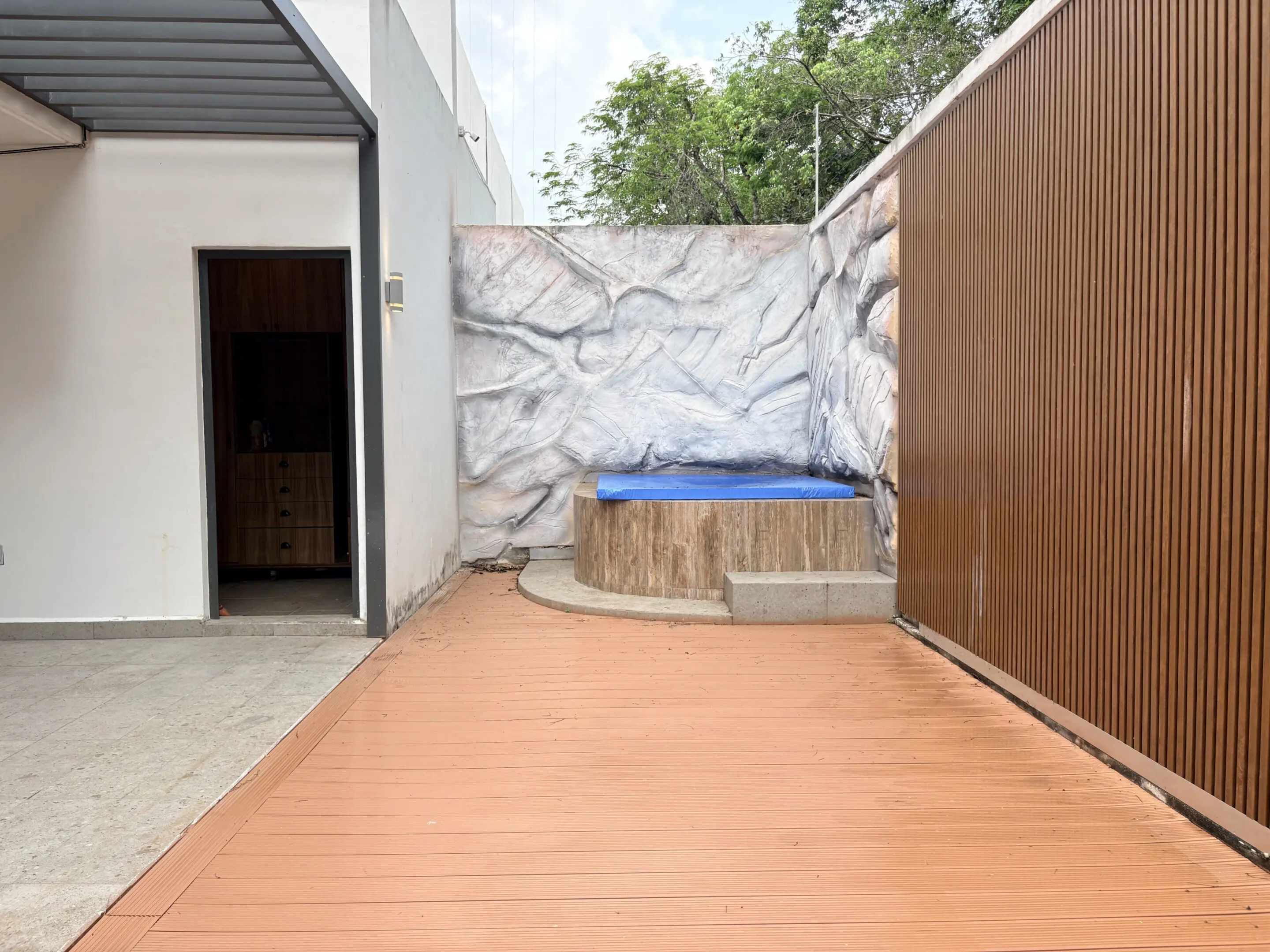 Outdoor wooden patio with blue-covered hot tub