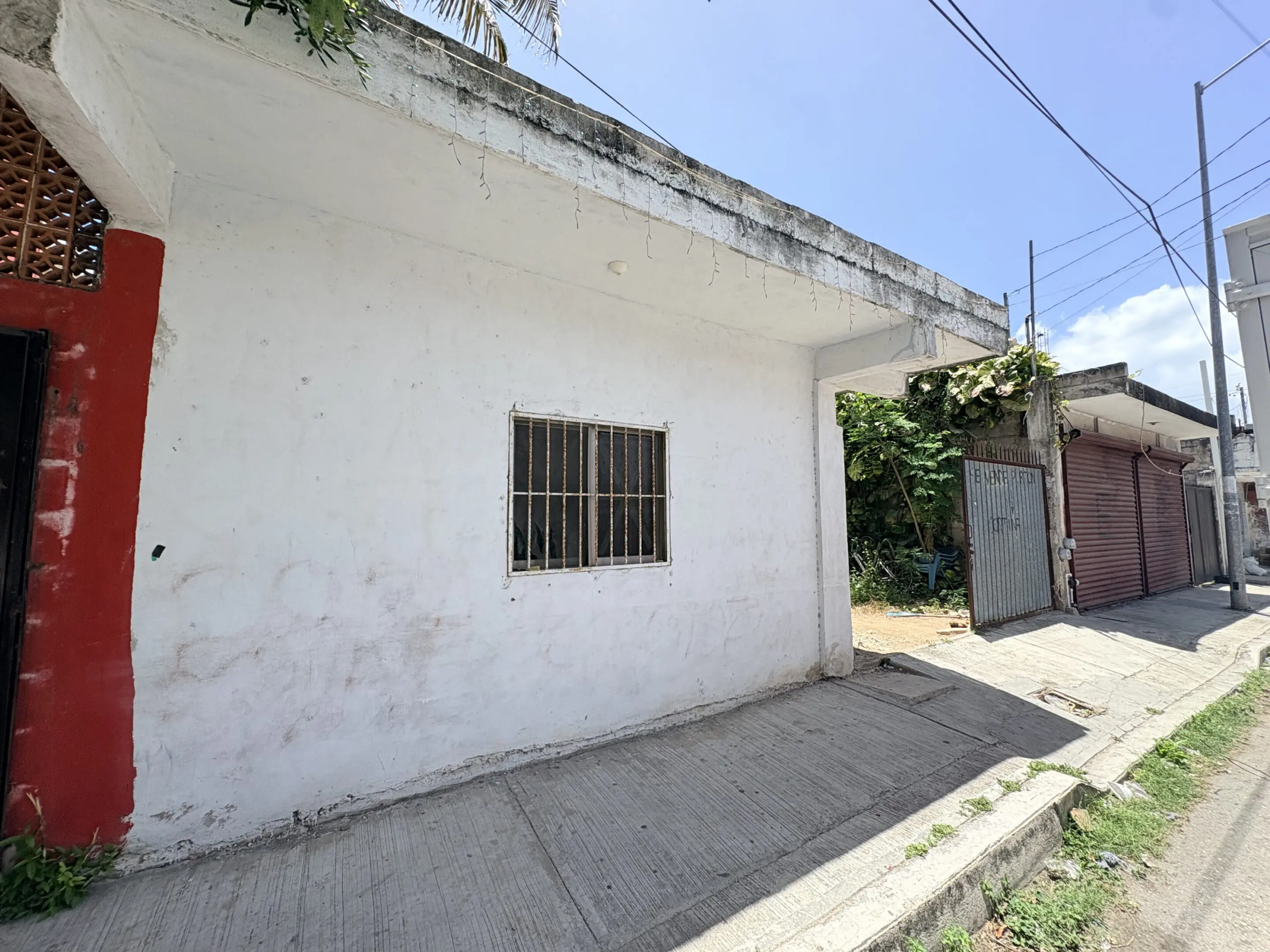 White storefront with barred window on sidewalk