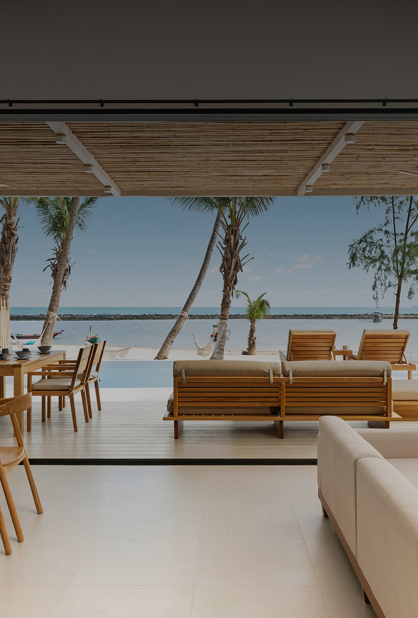 Beachfront patio with wooden furniture and view.
