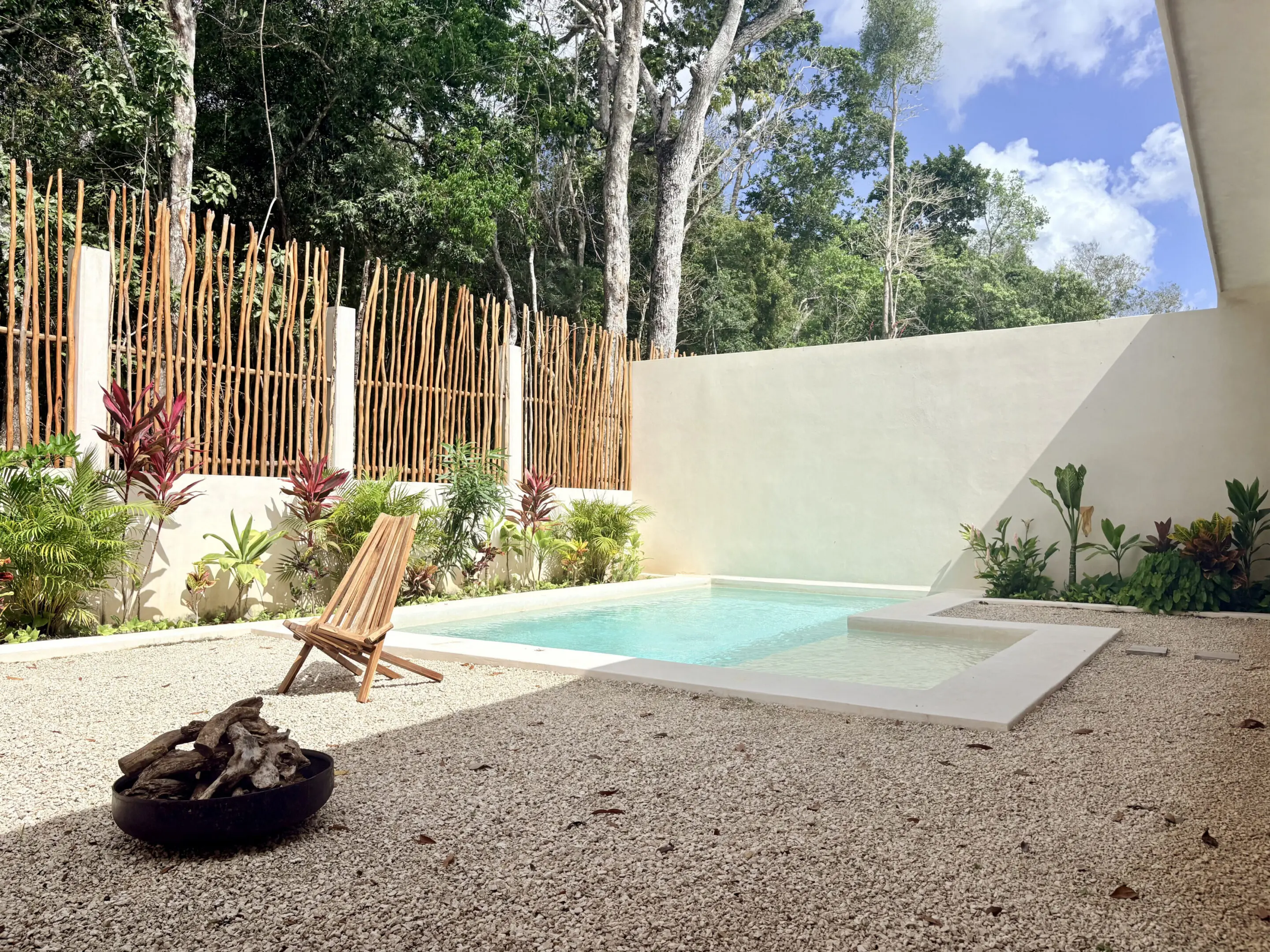 Tropical backyard plunge pool with wooden chair