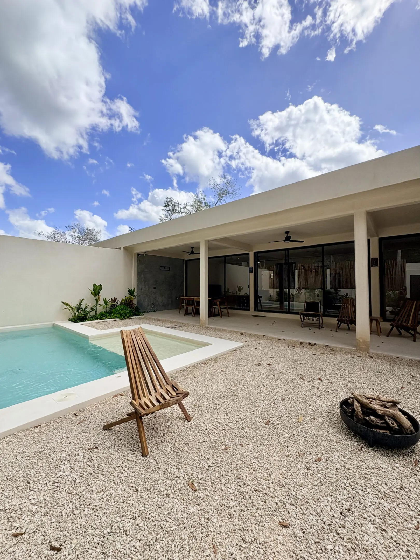 Minimalist patio with pool, wooden chair, fire pit