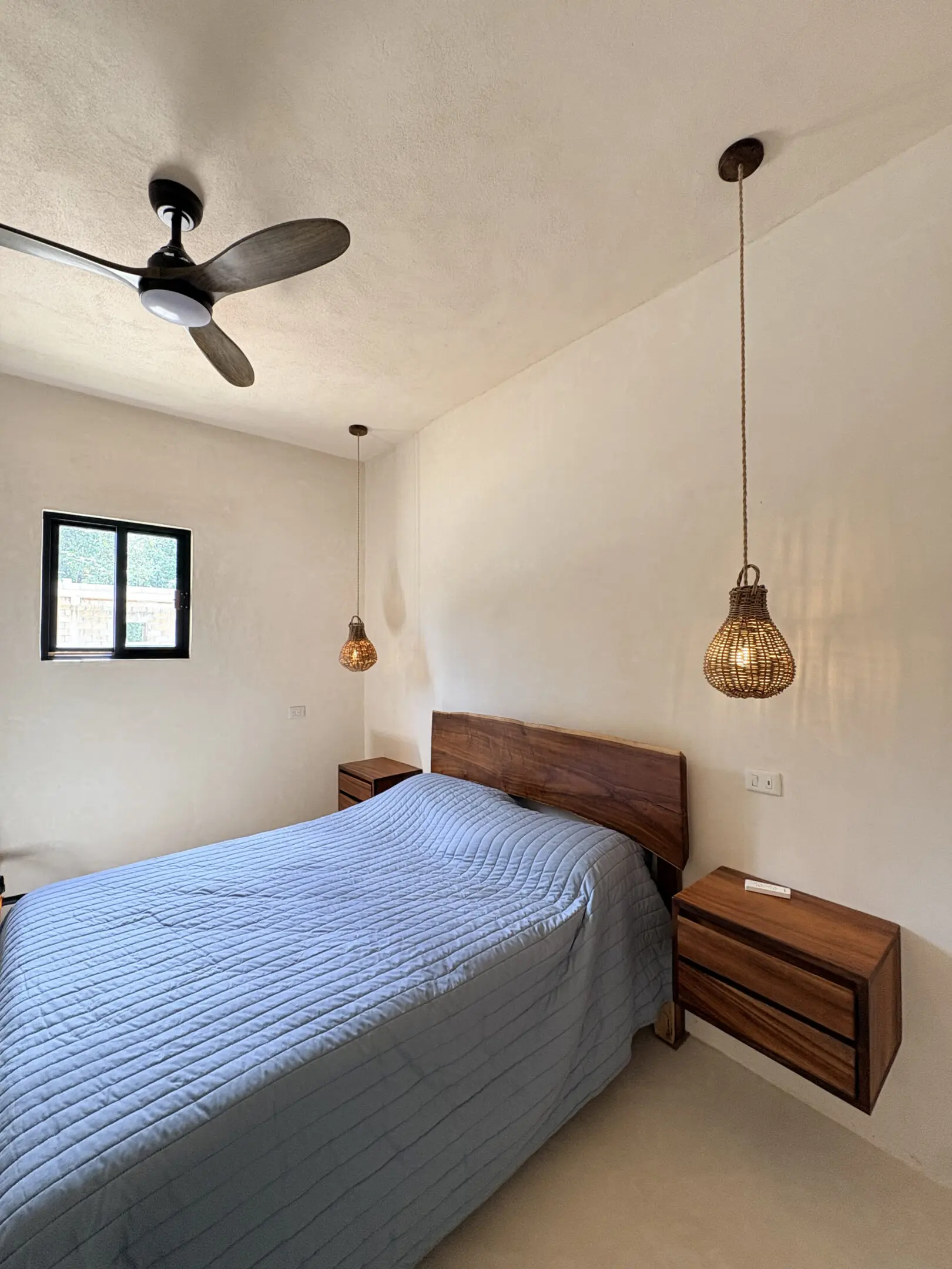 Bedroom with blue quilt, wooden headboard, pendant lights