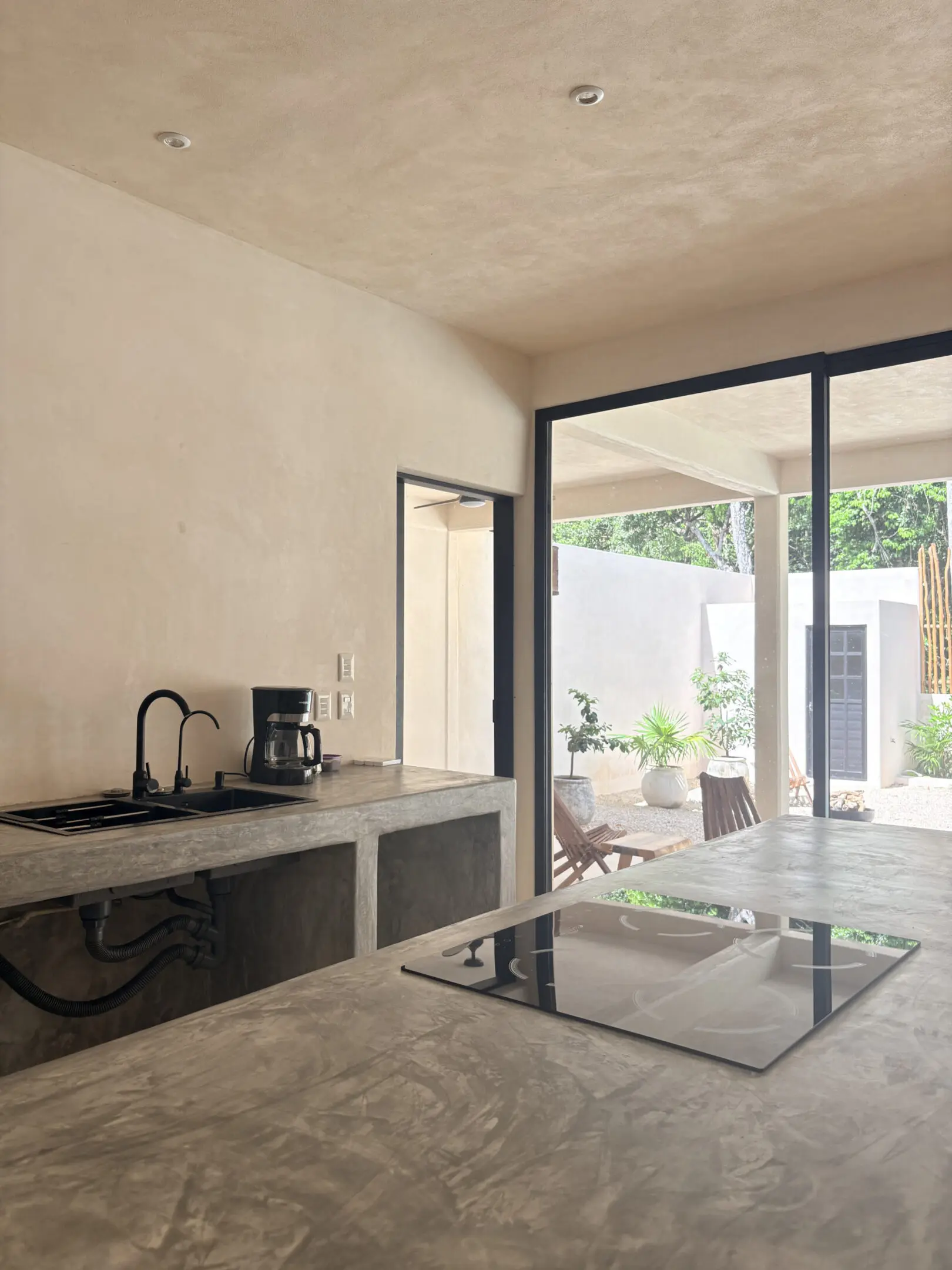 Minimal concrete kitchen opening to outdoor patio