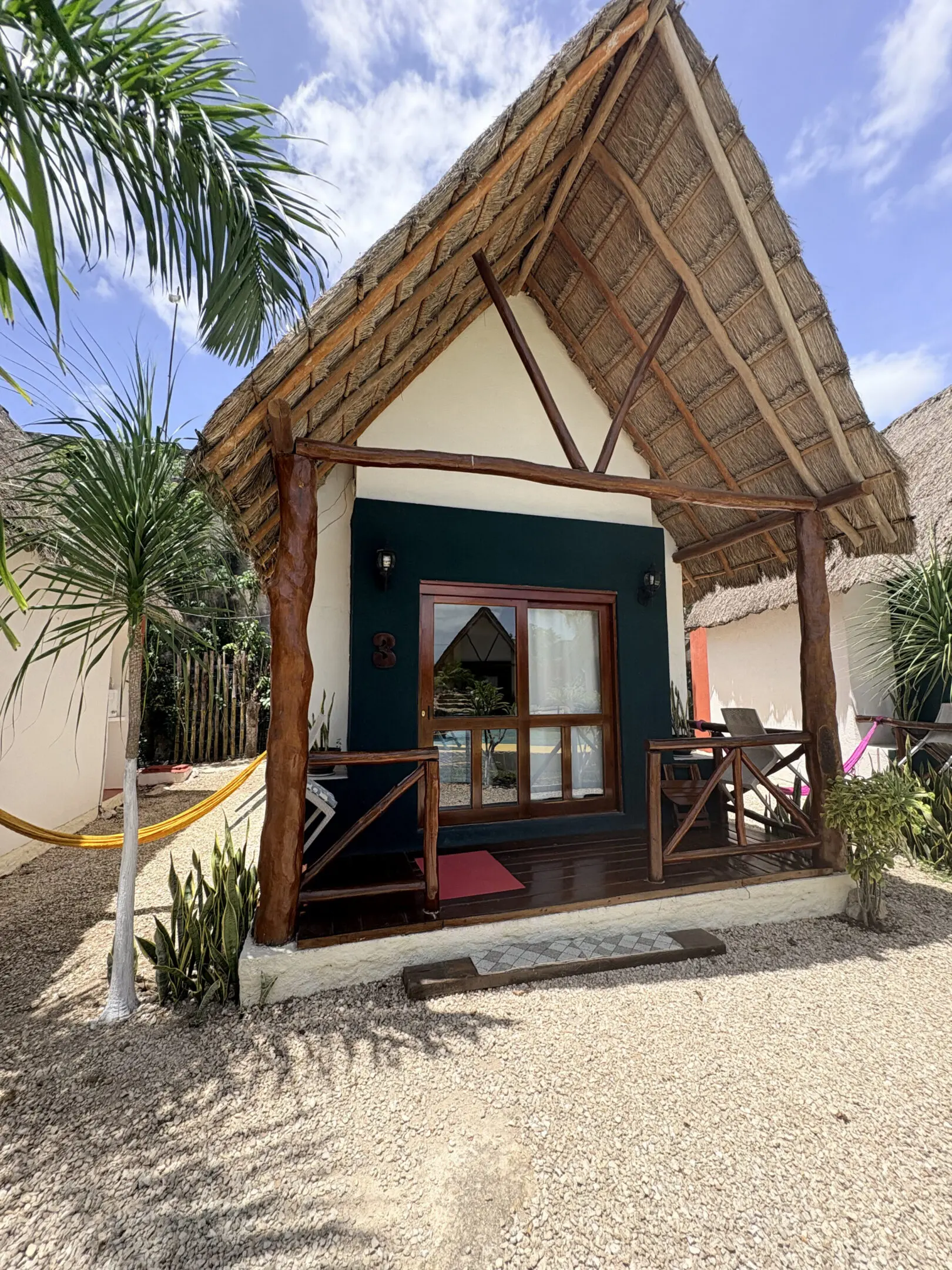 Thatched-roof tropical bungalow with hammock porch