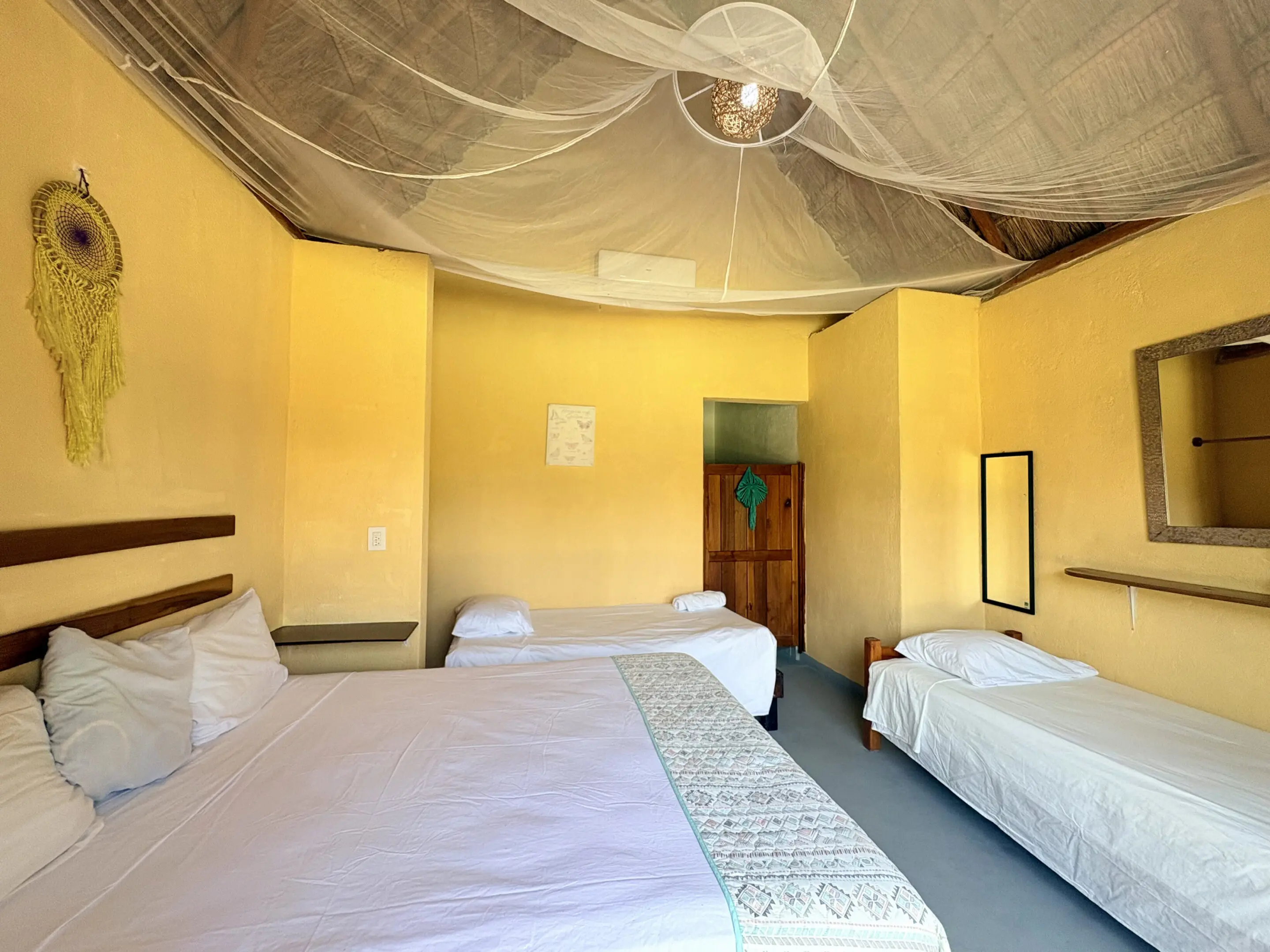 Yellow bedroom with three beds and mosquito net