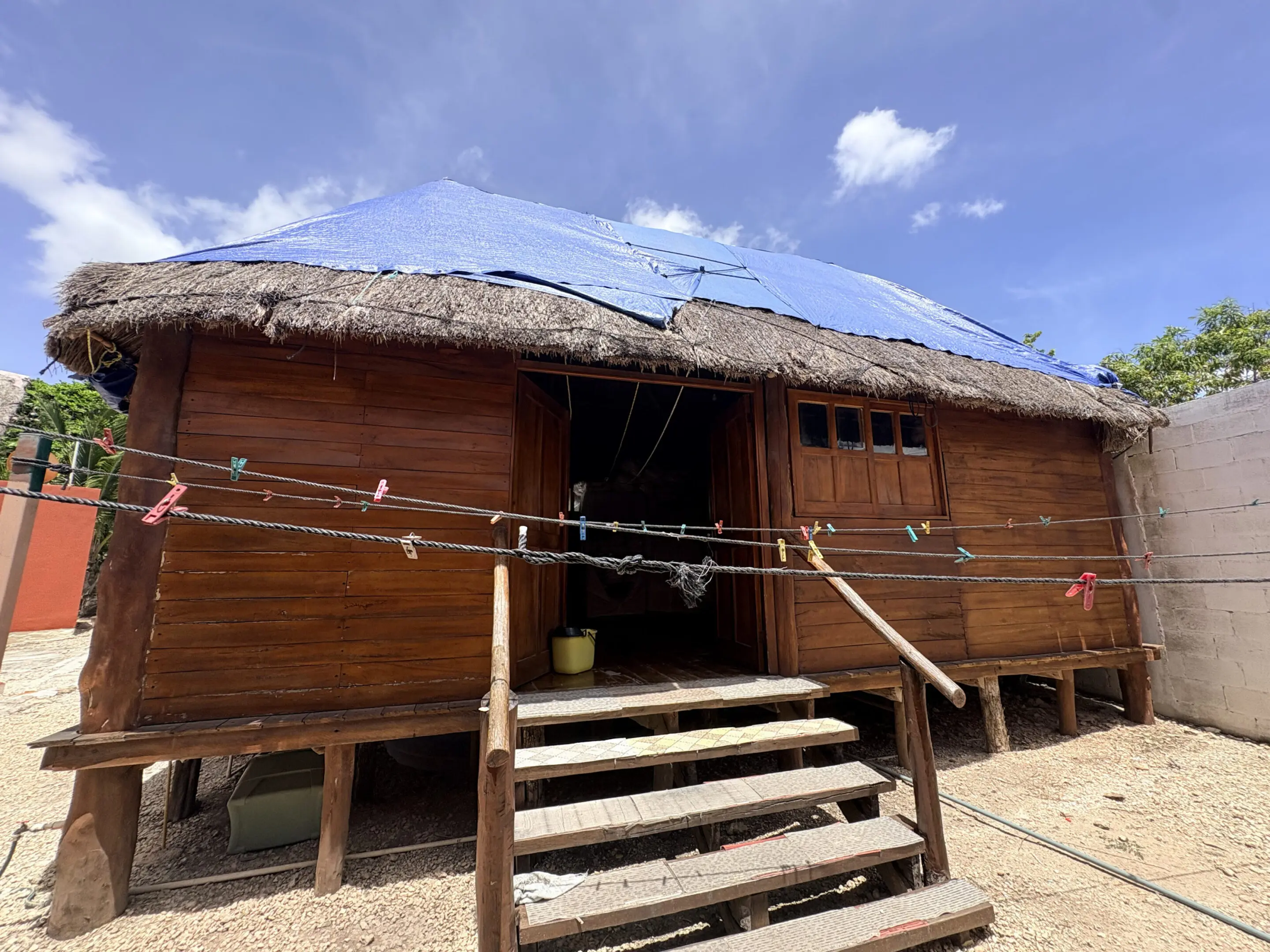 Traditional wooden hut with blue tarp roof