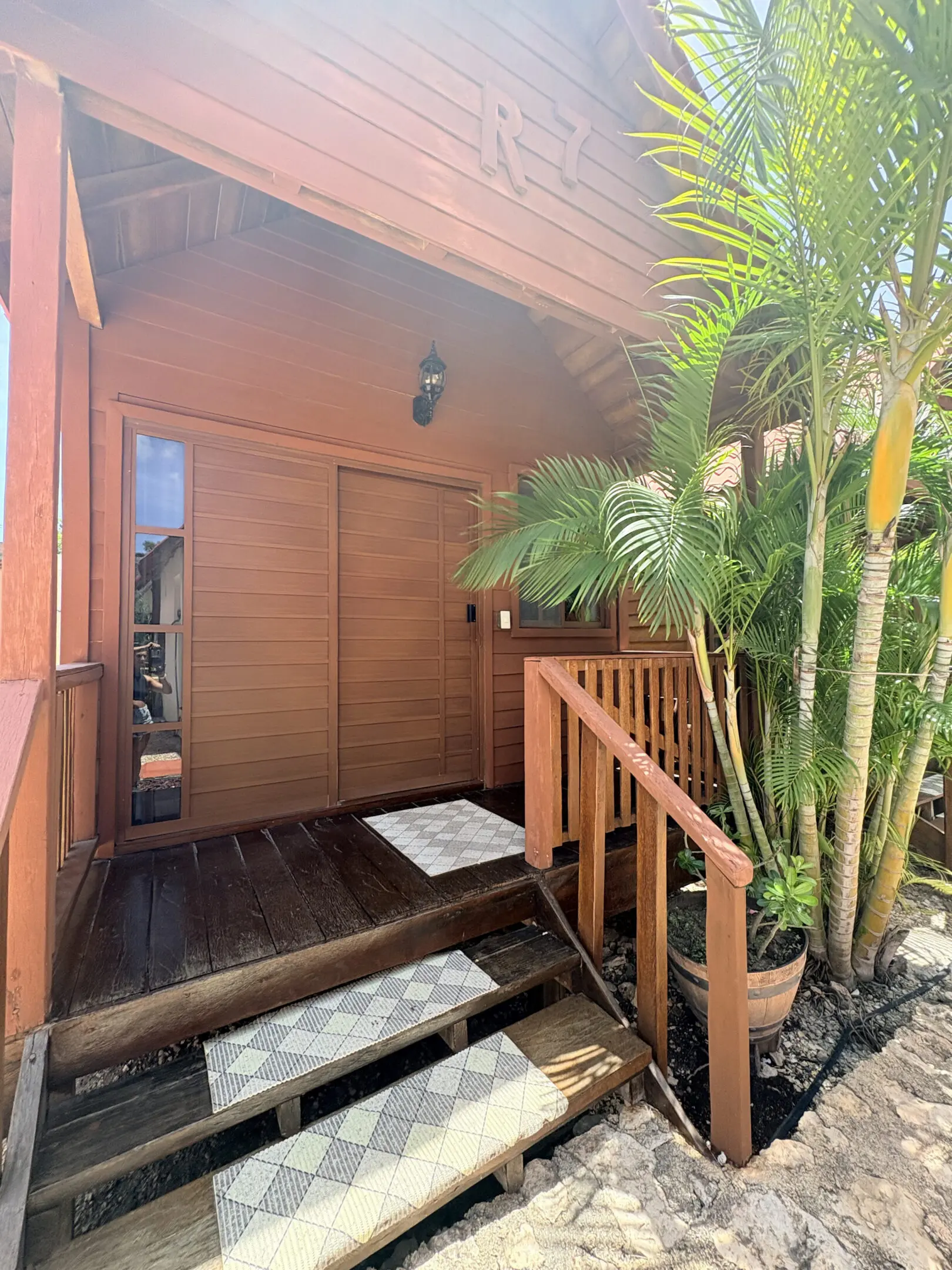 Tropical wooden bungalow entrance with palm plants