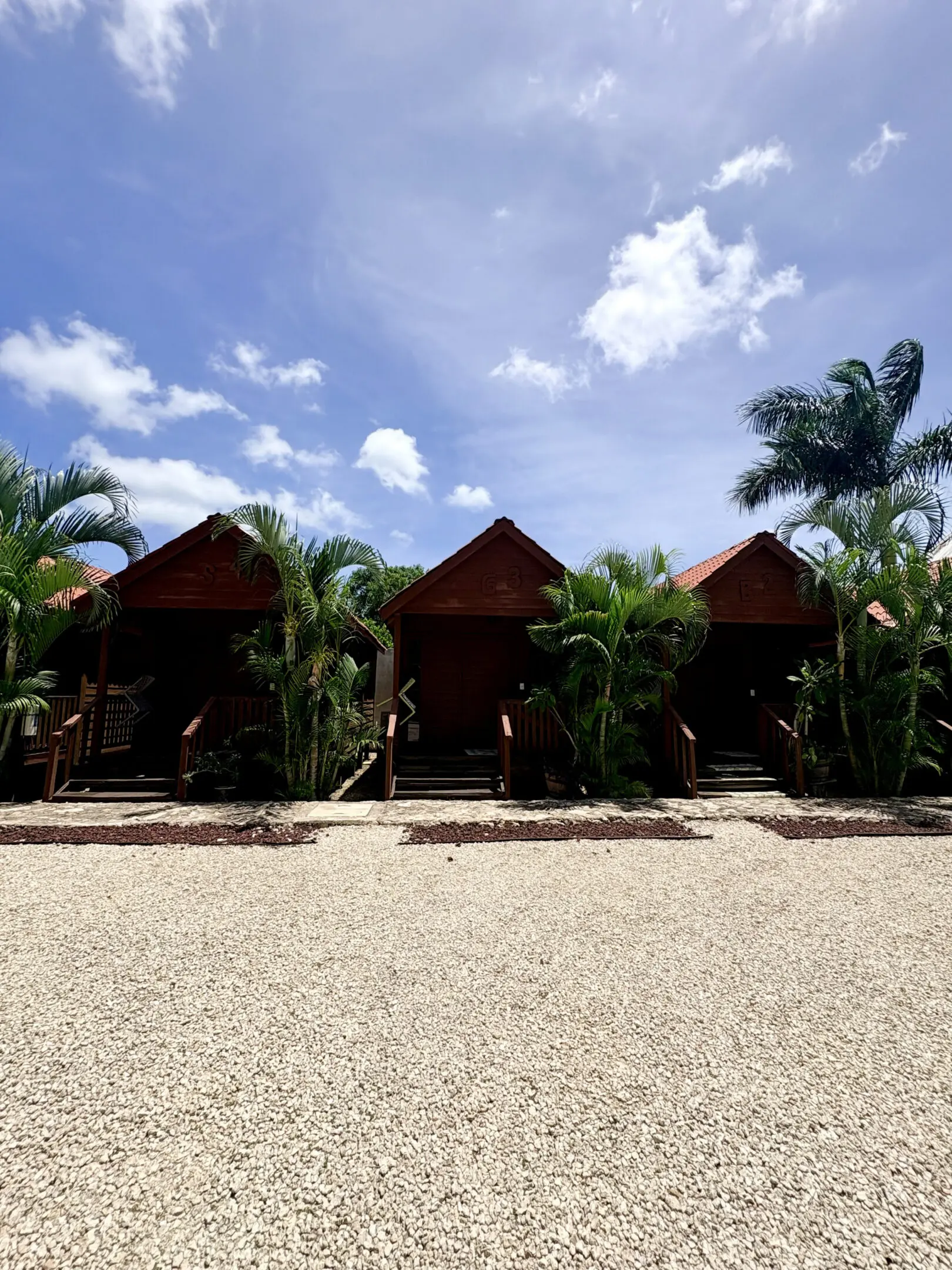 Three wooden bungalows framed by palm trees