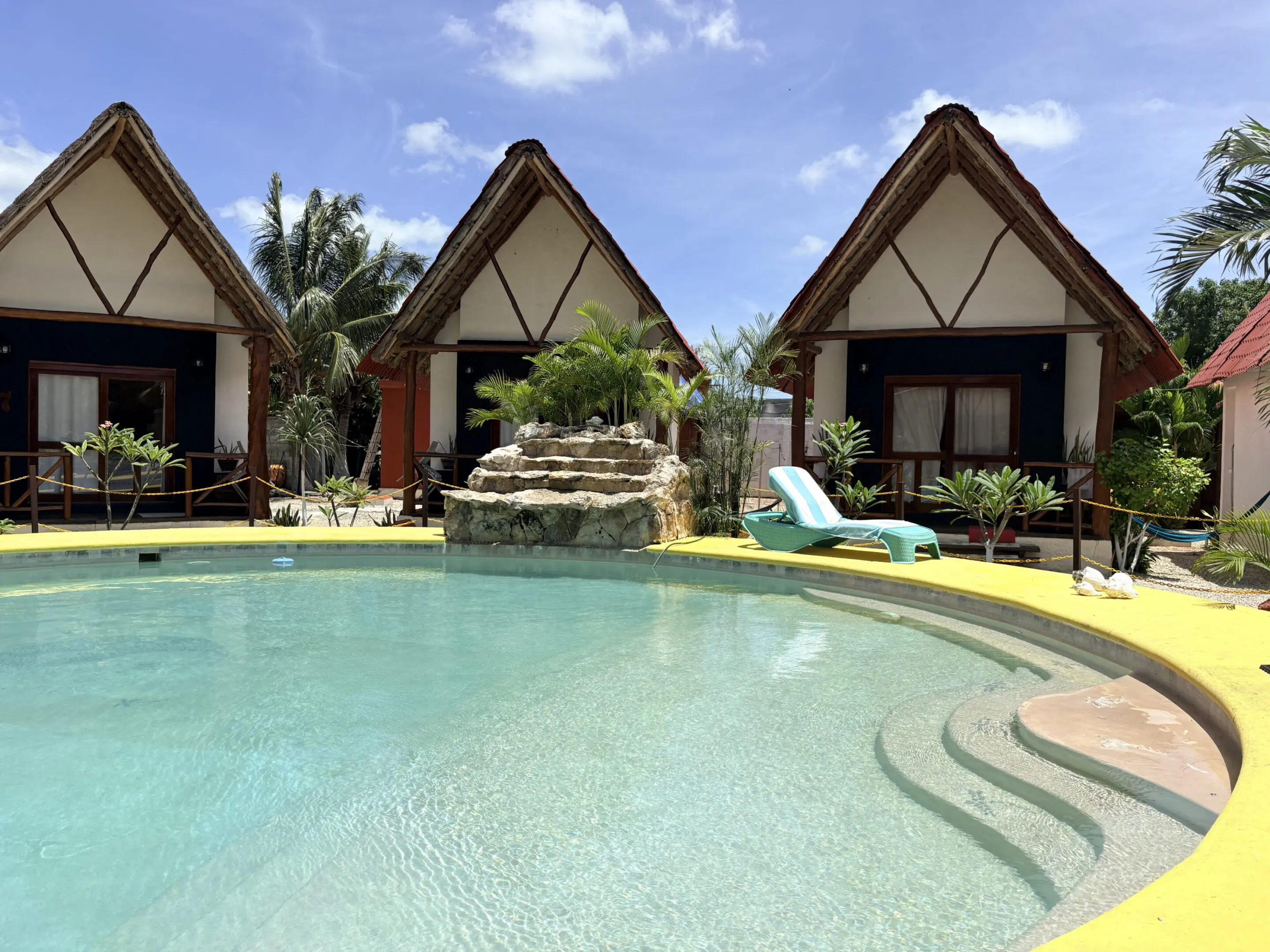 Three thatched bungalows by tropical resort pool