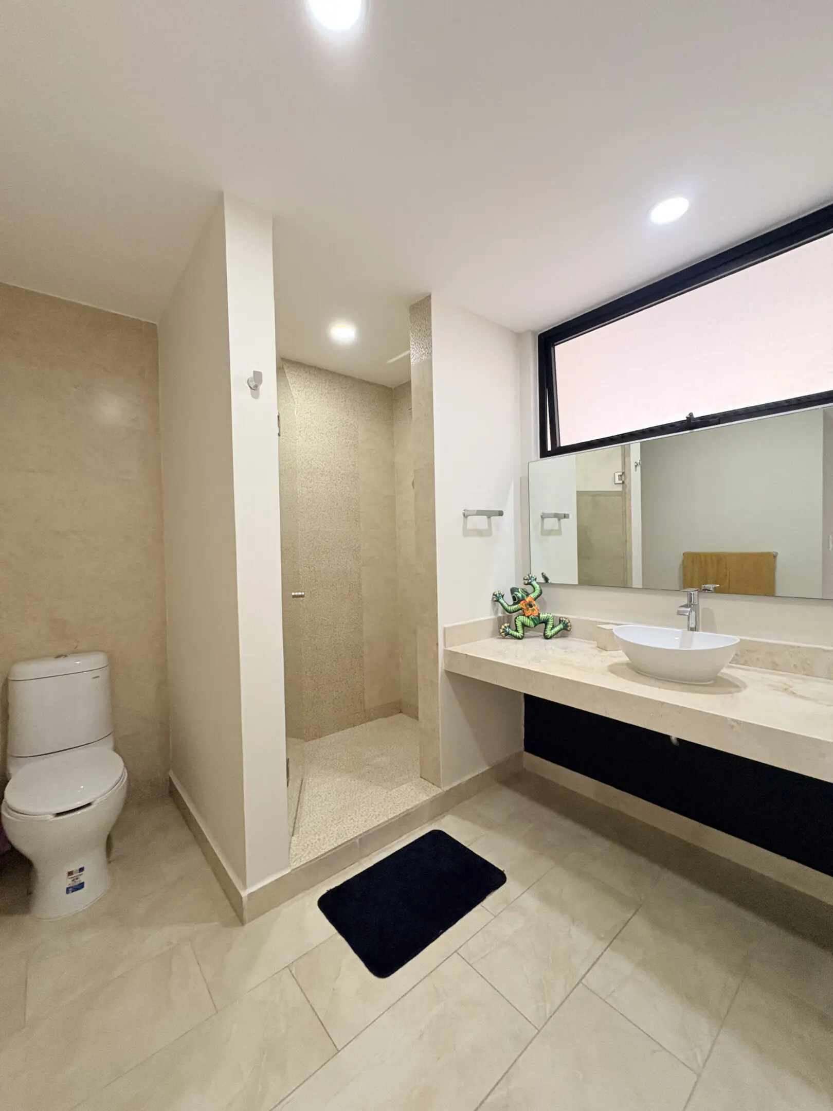 Modern beige bathroom with shower, sink, toilet