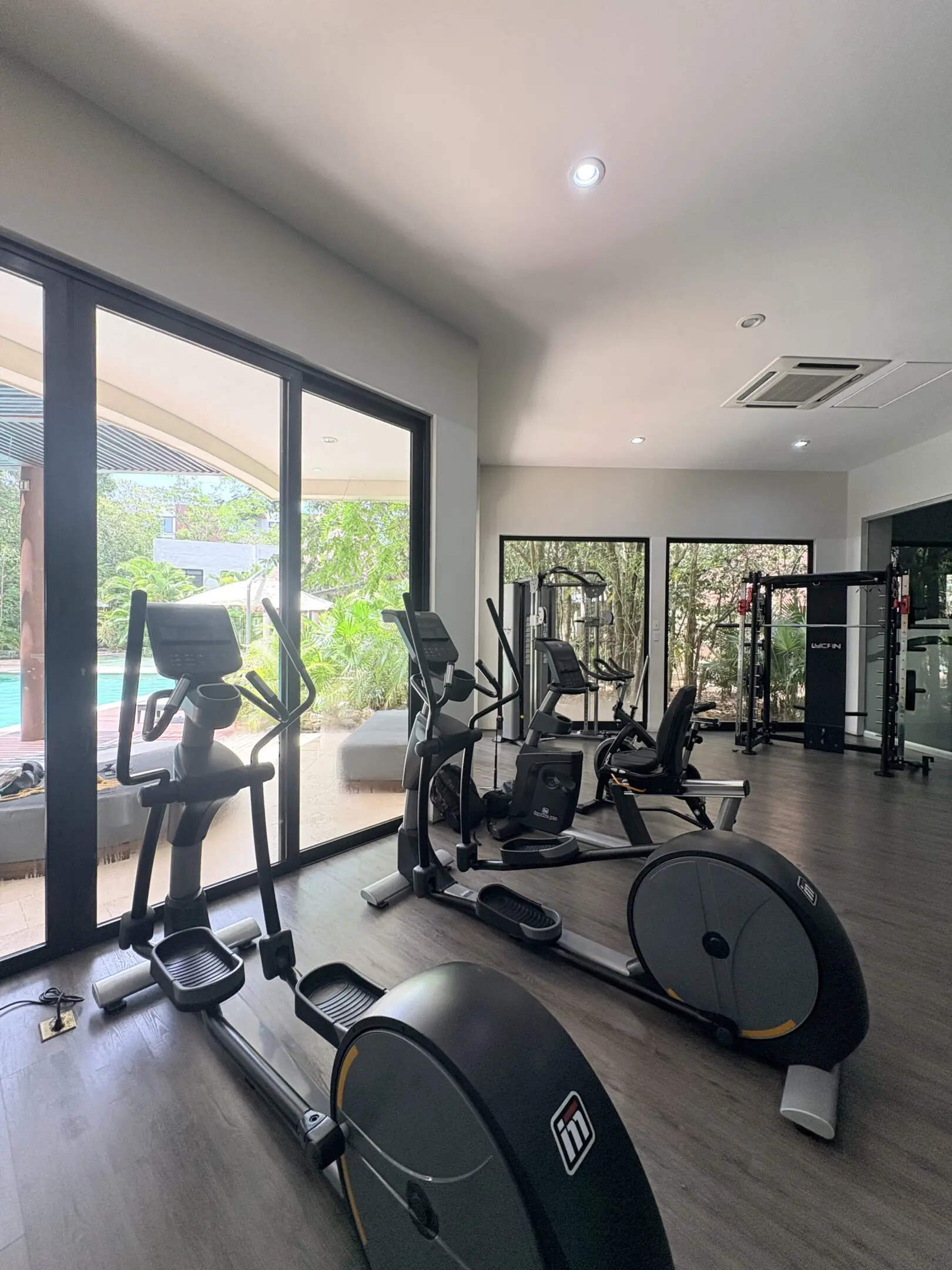 Home gym with ellipticals overlooking outdoor pool