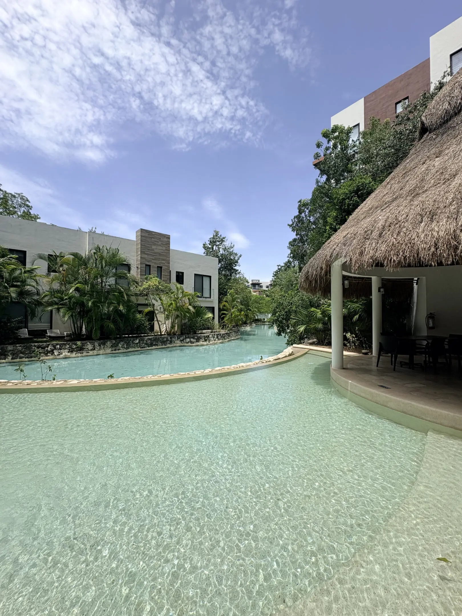 Tropical resort pool with palapa and villas