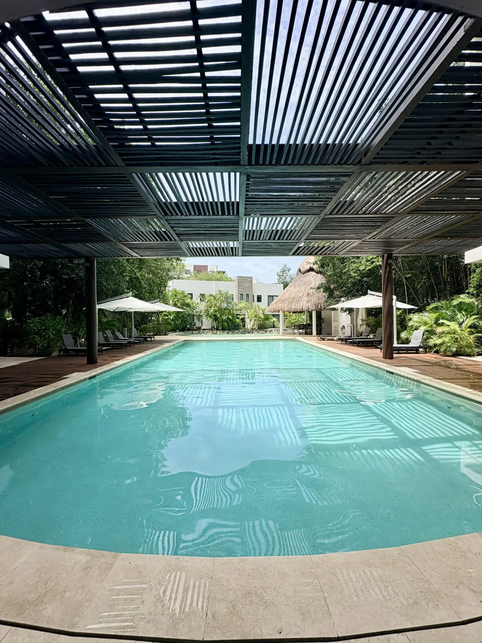 Tropical outdoor pool with pergola and umbrellas