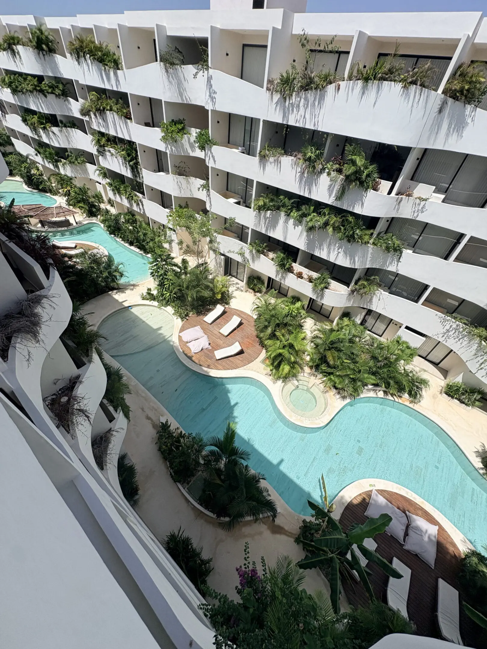 Curved white resort building with winding pool