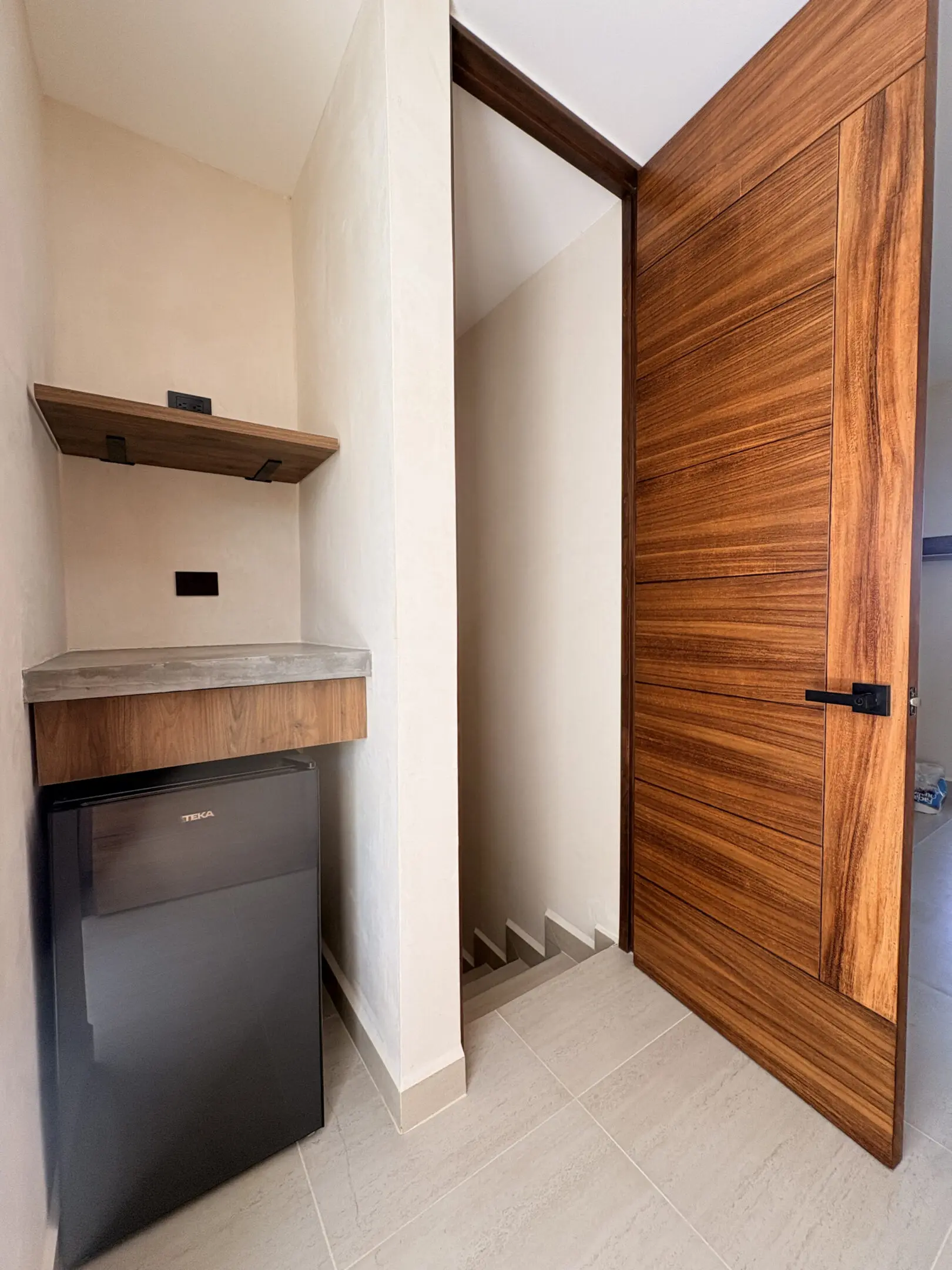 Small hallway with wooden door and mini-fridge