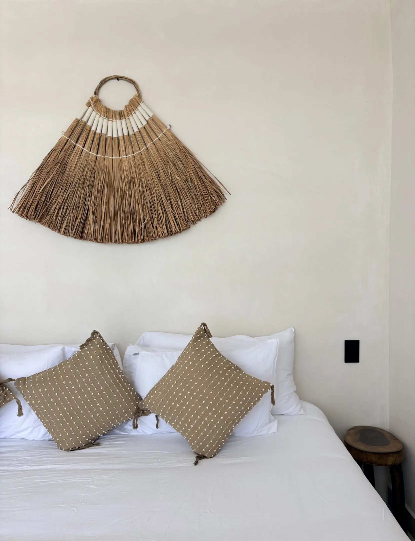 White bed with brown pillows and straw decor