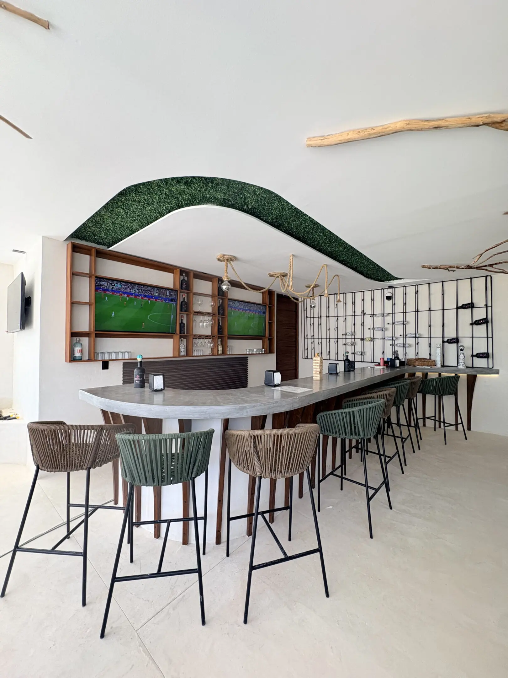 Modern curved bar with wicker stools and TVs