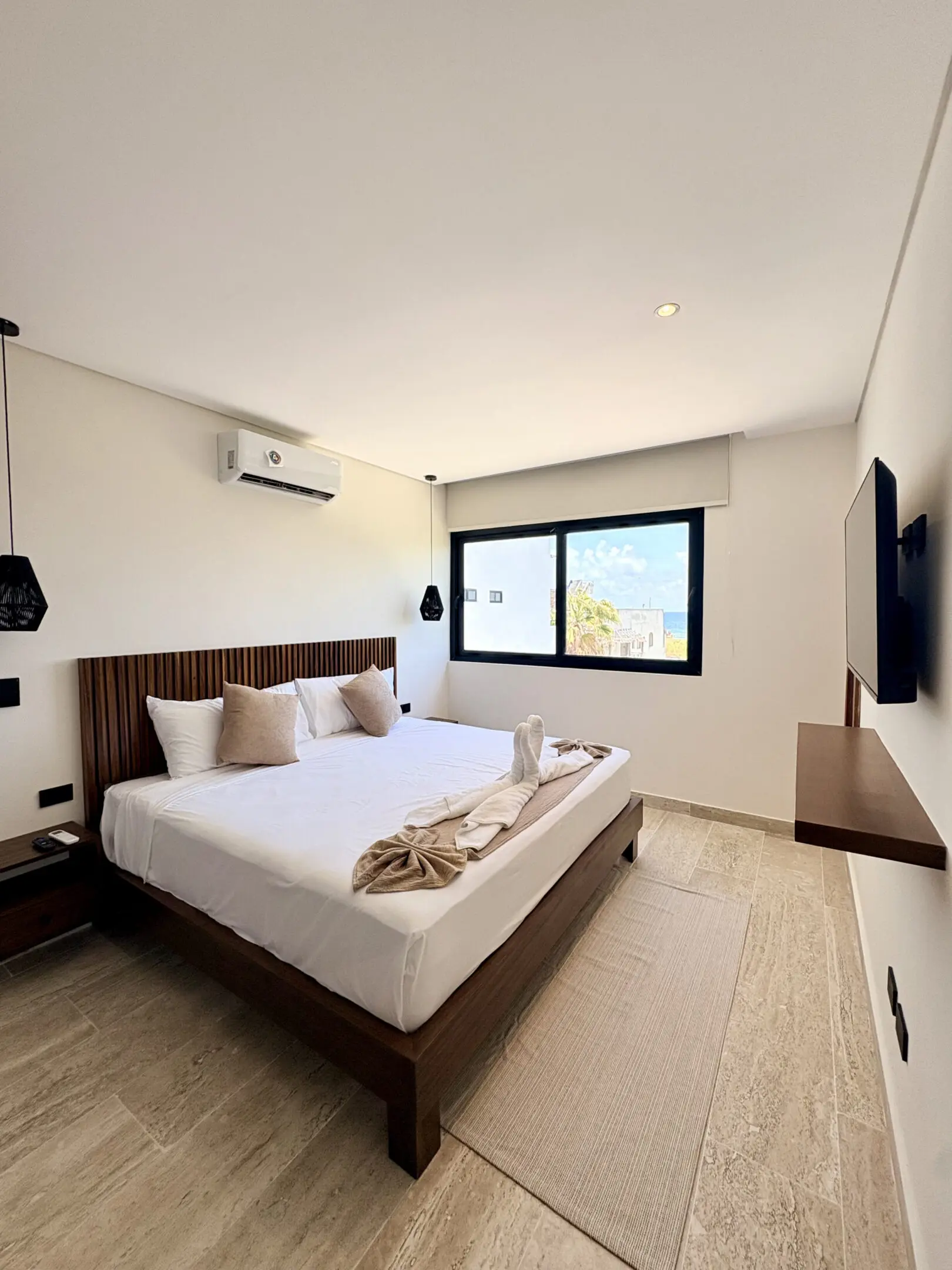 Bright modern bedroom with bed, window, TV