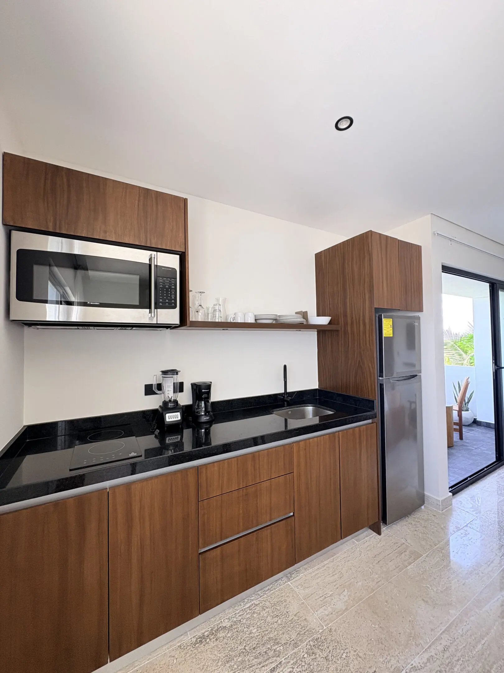 Modern kitchenette with wooden cabinets, black countertop