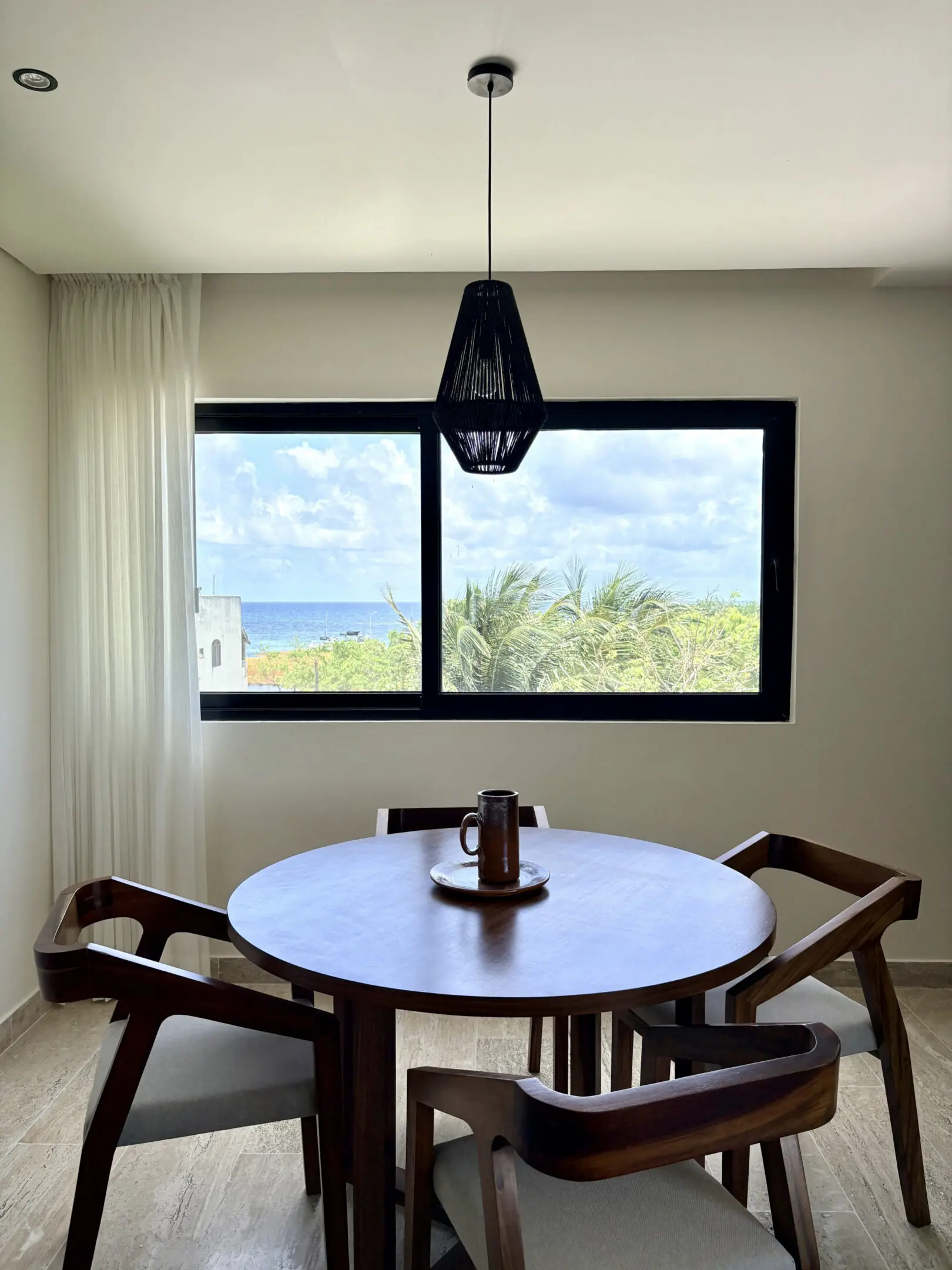 Round wooden dining table by window with ocean