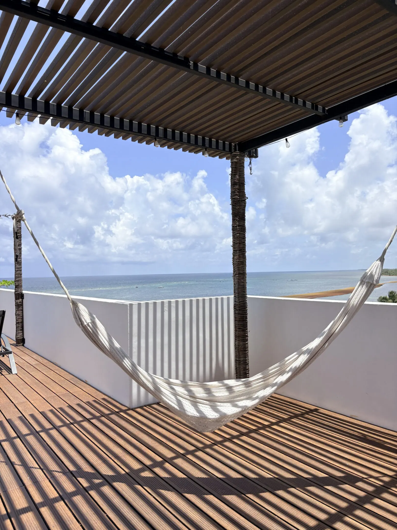 Hammock on shaded seaside deck overlooking ocean