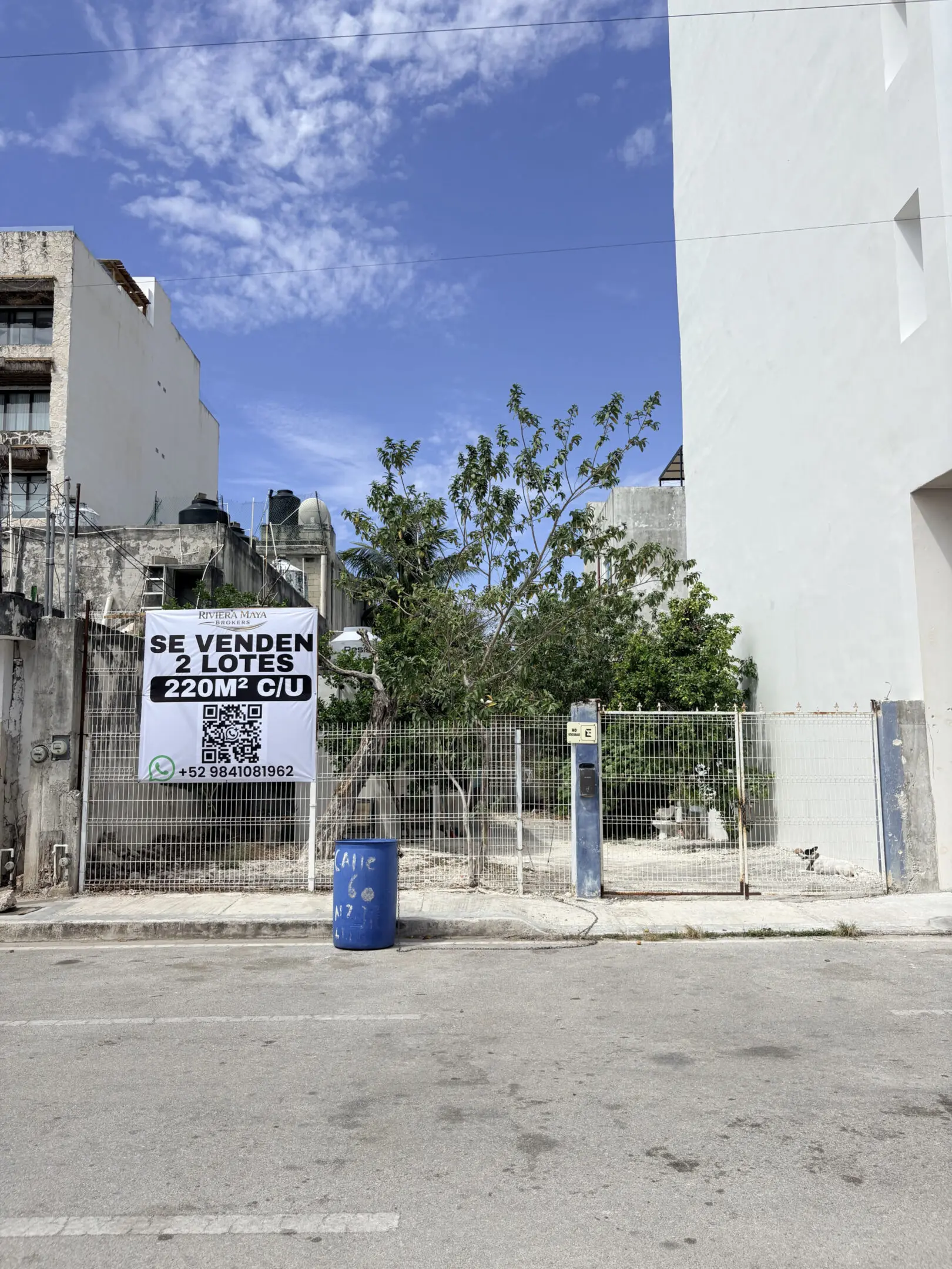 Vacant urban fenced lot with for-sale sign