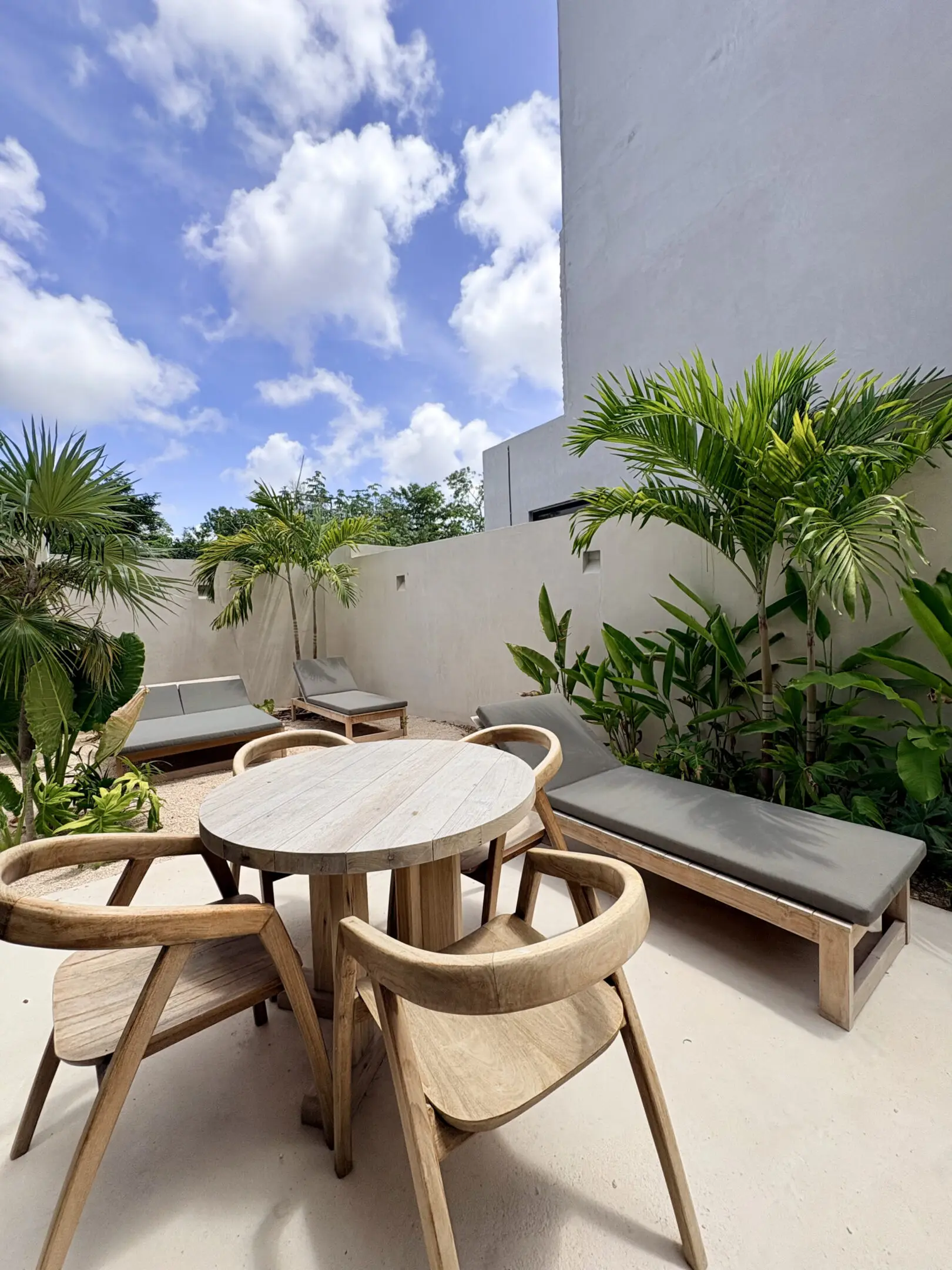 Round wooden patio table with lounge chairs