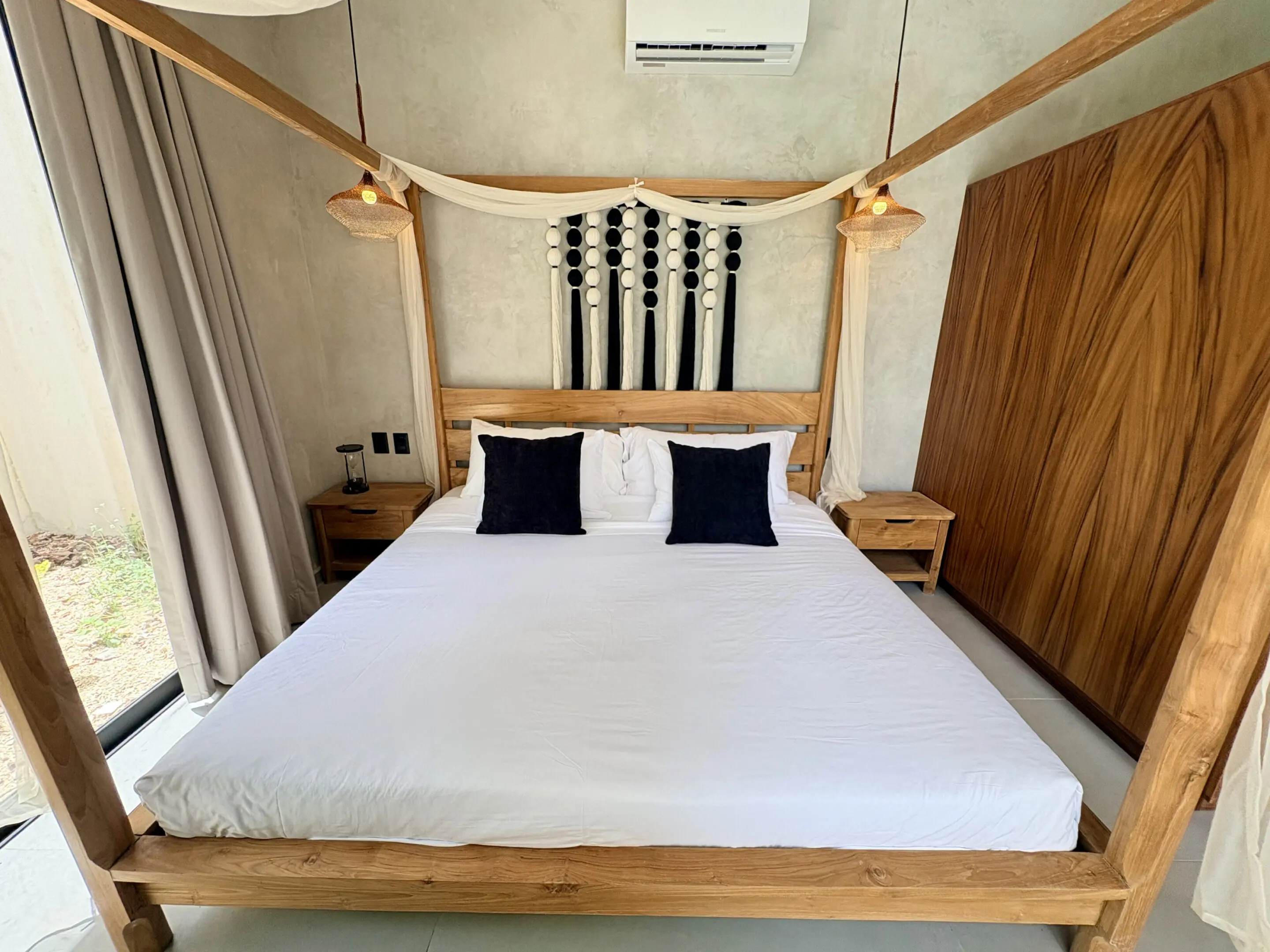 Minimalist wooden four-poster bed with white bedding