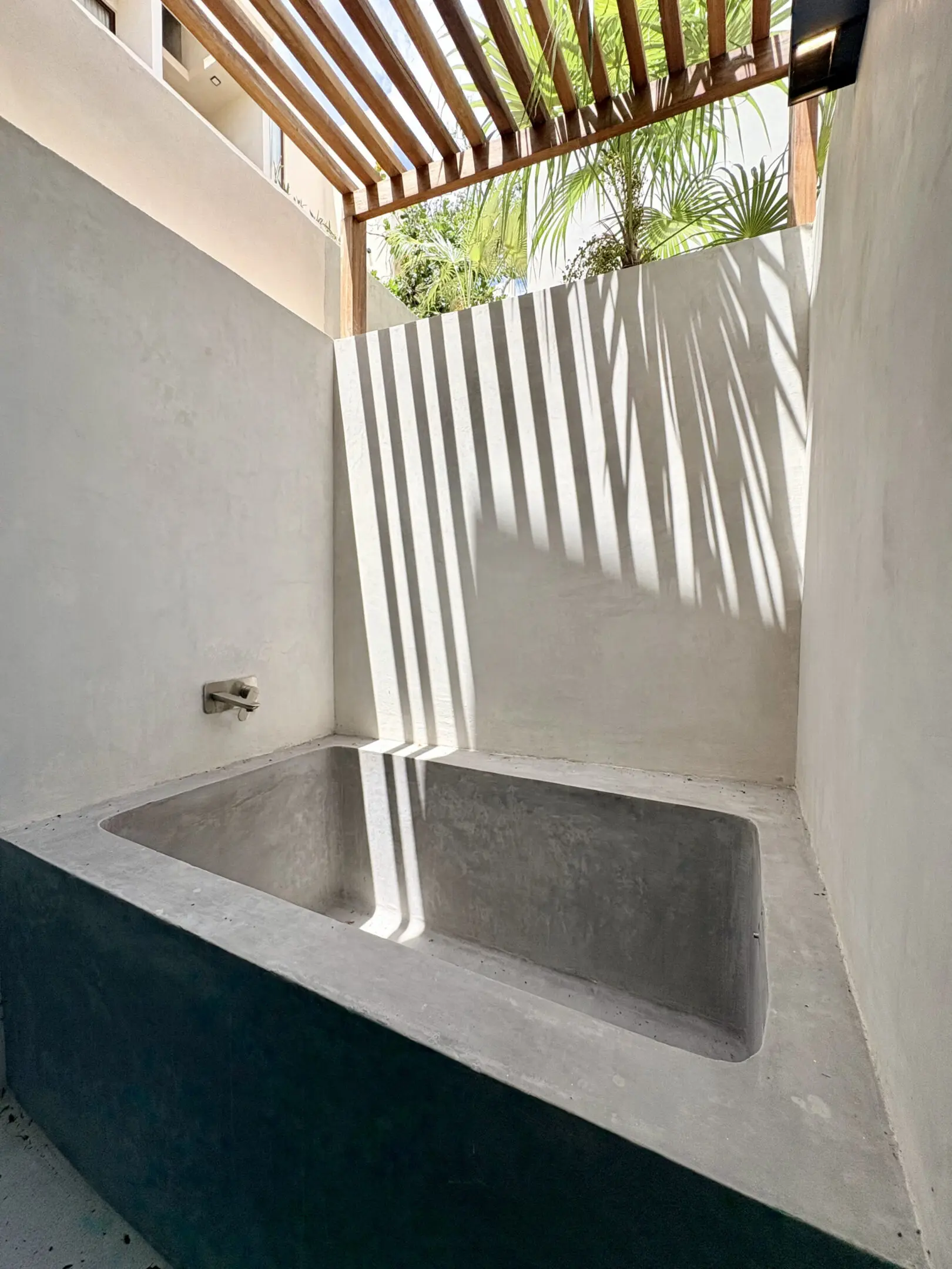 Sunlit concrete outdoor bathtub with striped shadows