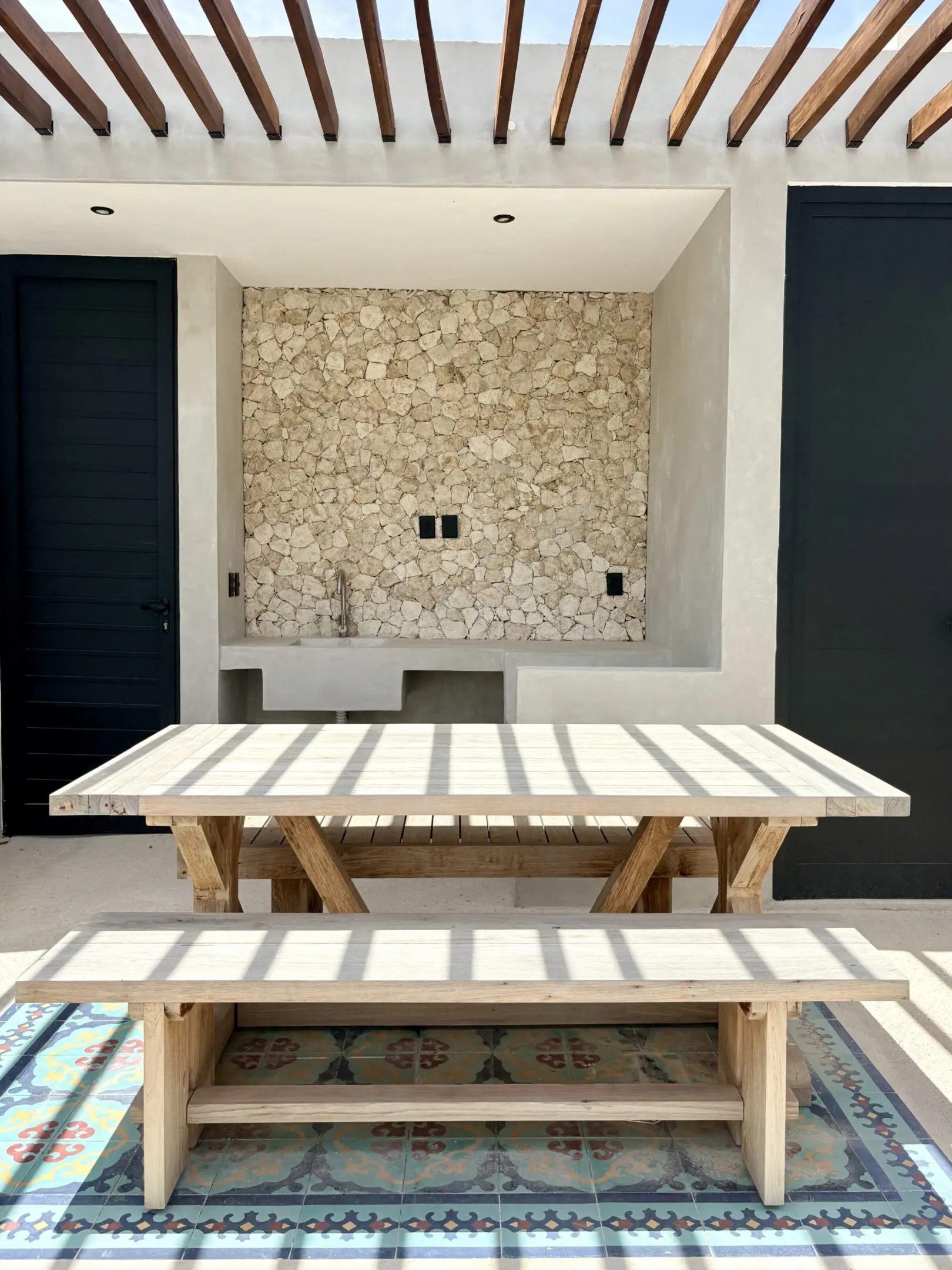 Sunlit wooden table and bench by stone wall