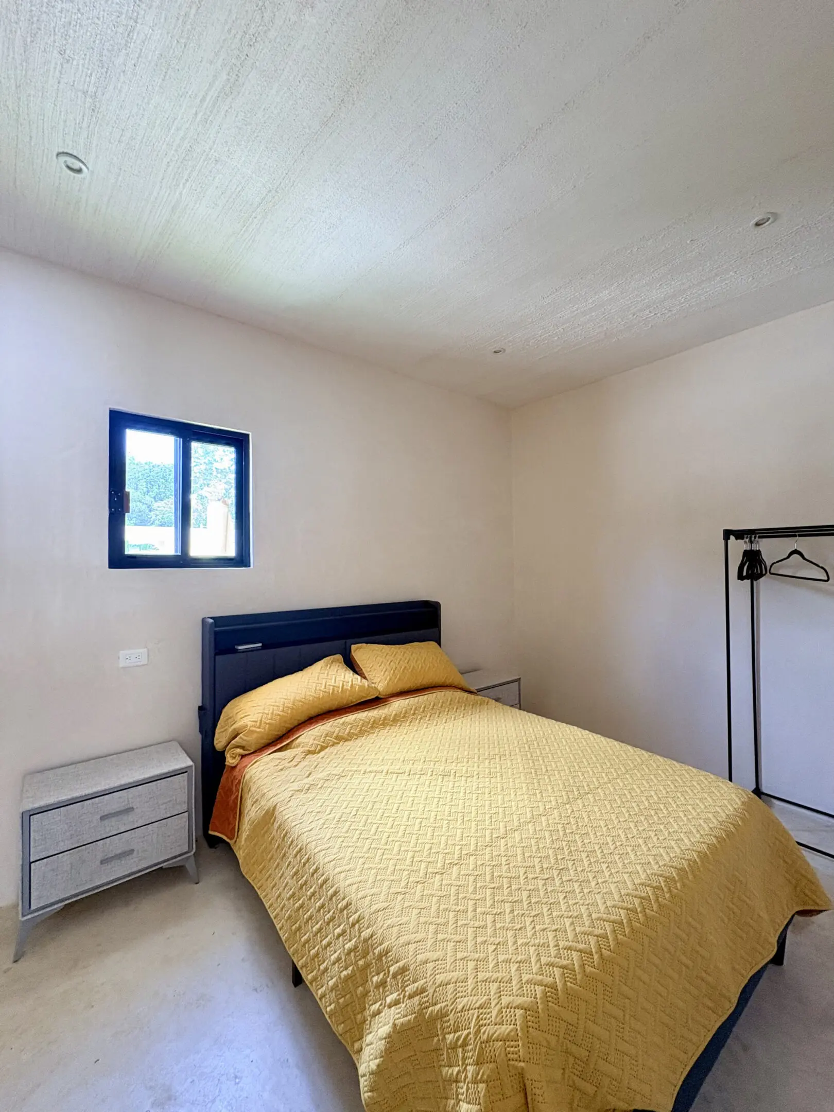 Minimal bedroom with yellow bedspread and window
