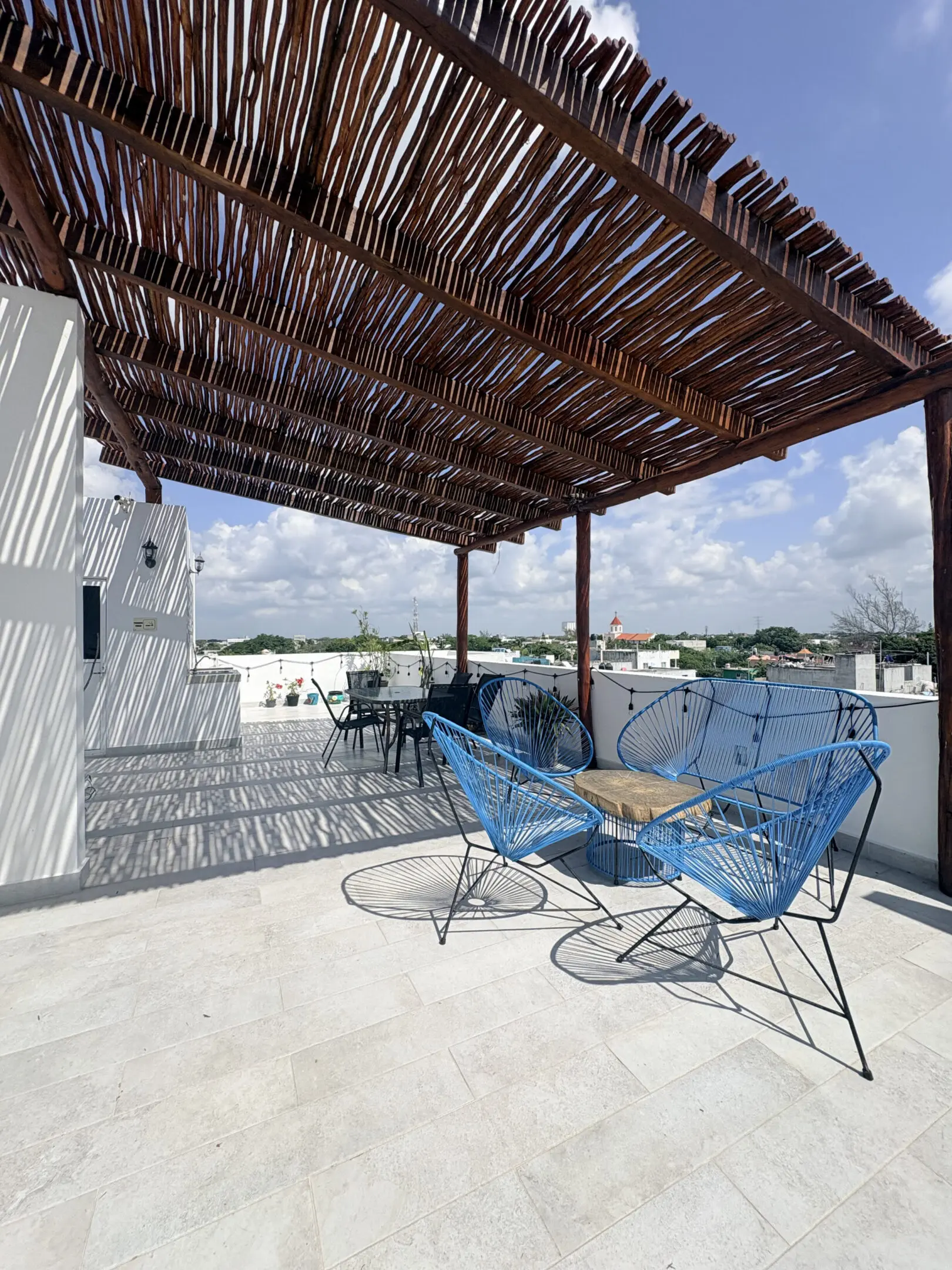 Rooftop terrace with wooden pergola and blue chairs