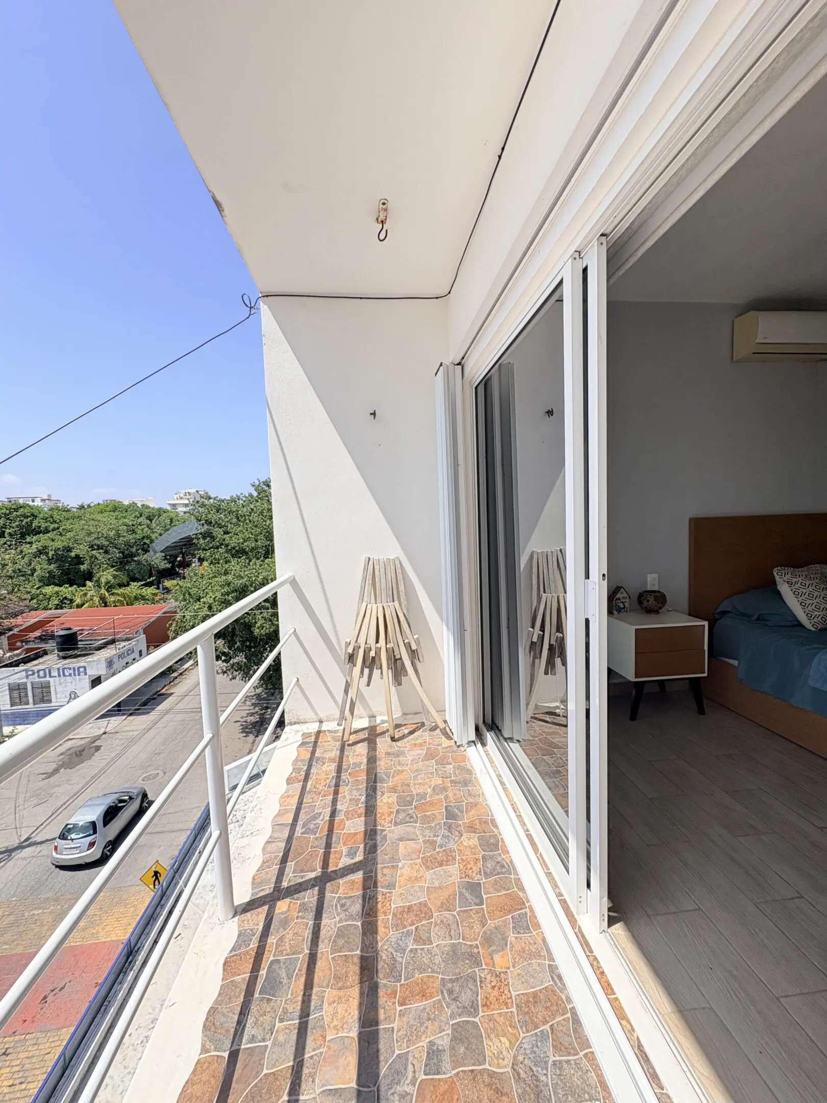 Sunlit tiled balcony with stool and sliding door