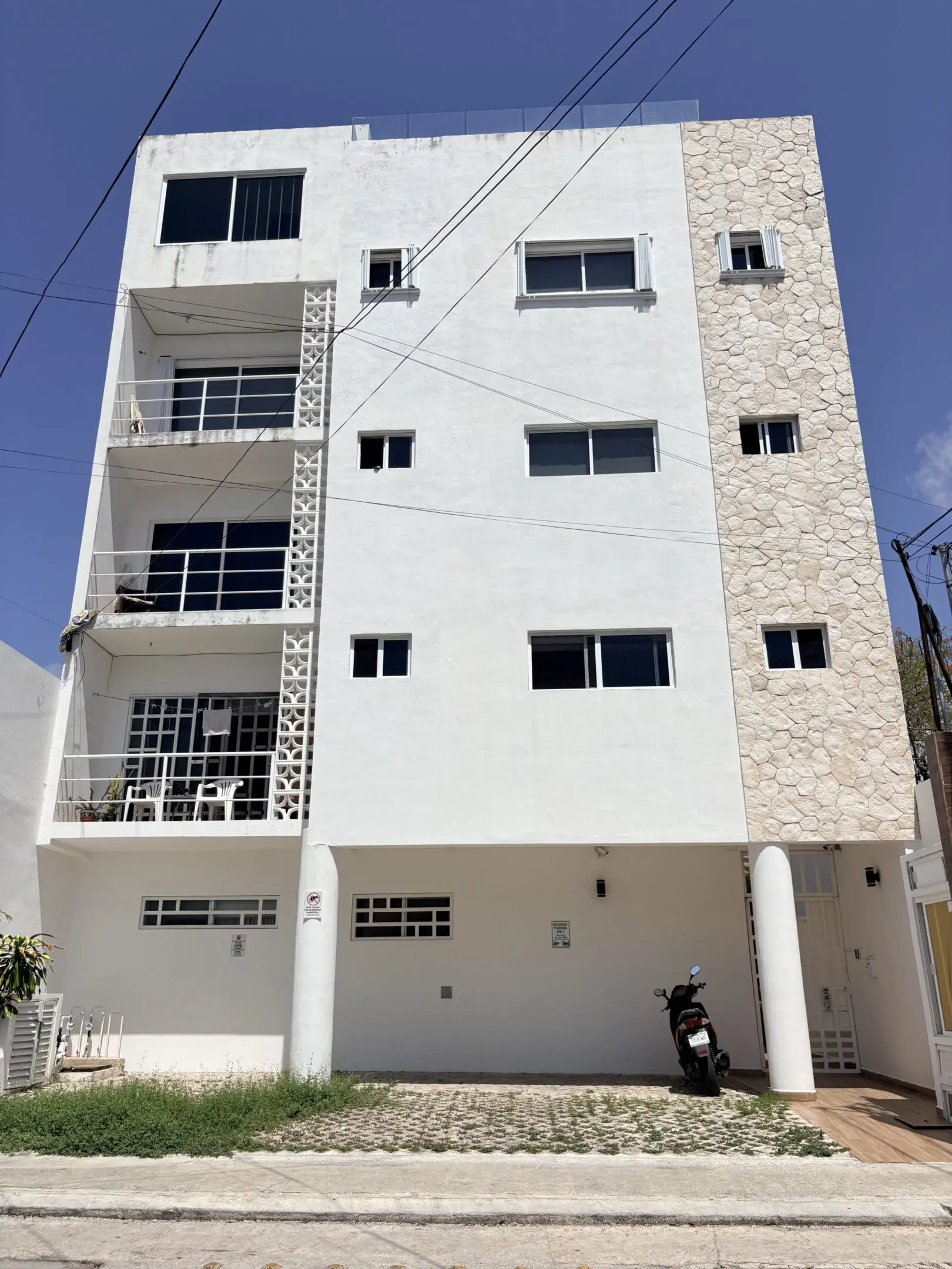 White apartment building with balconies and scooter