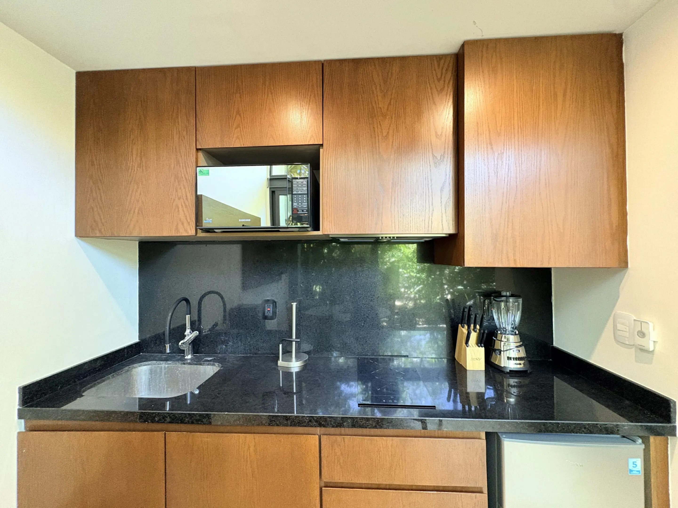 Small kitchenette with wooden cabinets and black countertop