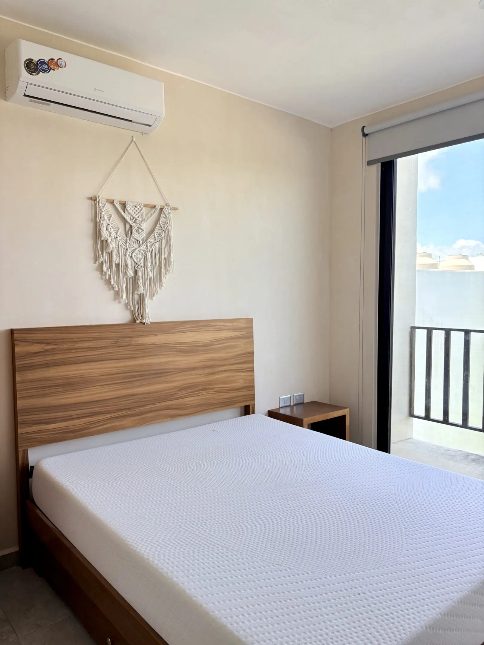 Minimalist bedroom with wooden headboard and balcony