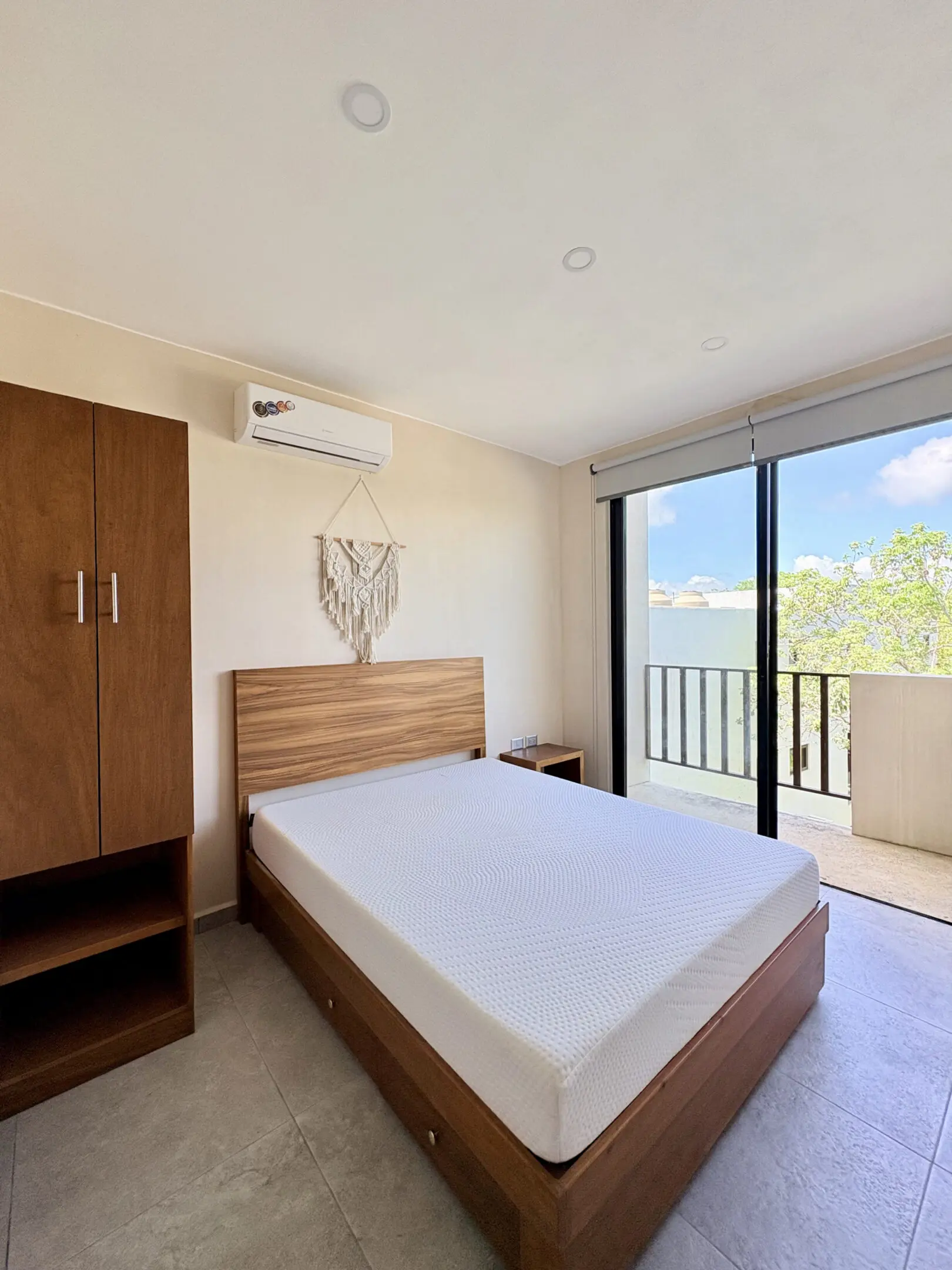 Bright minimal bedroom with wooden bed and balcony