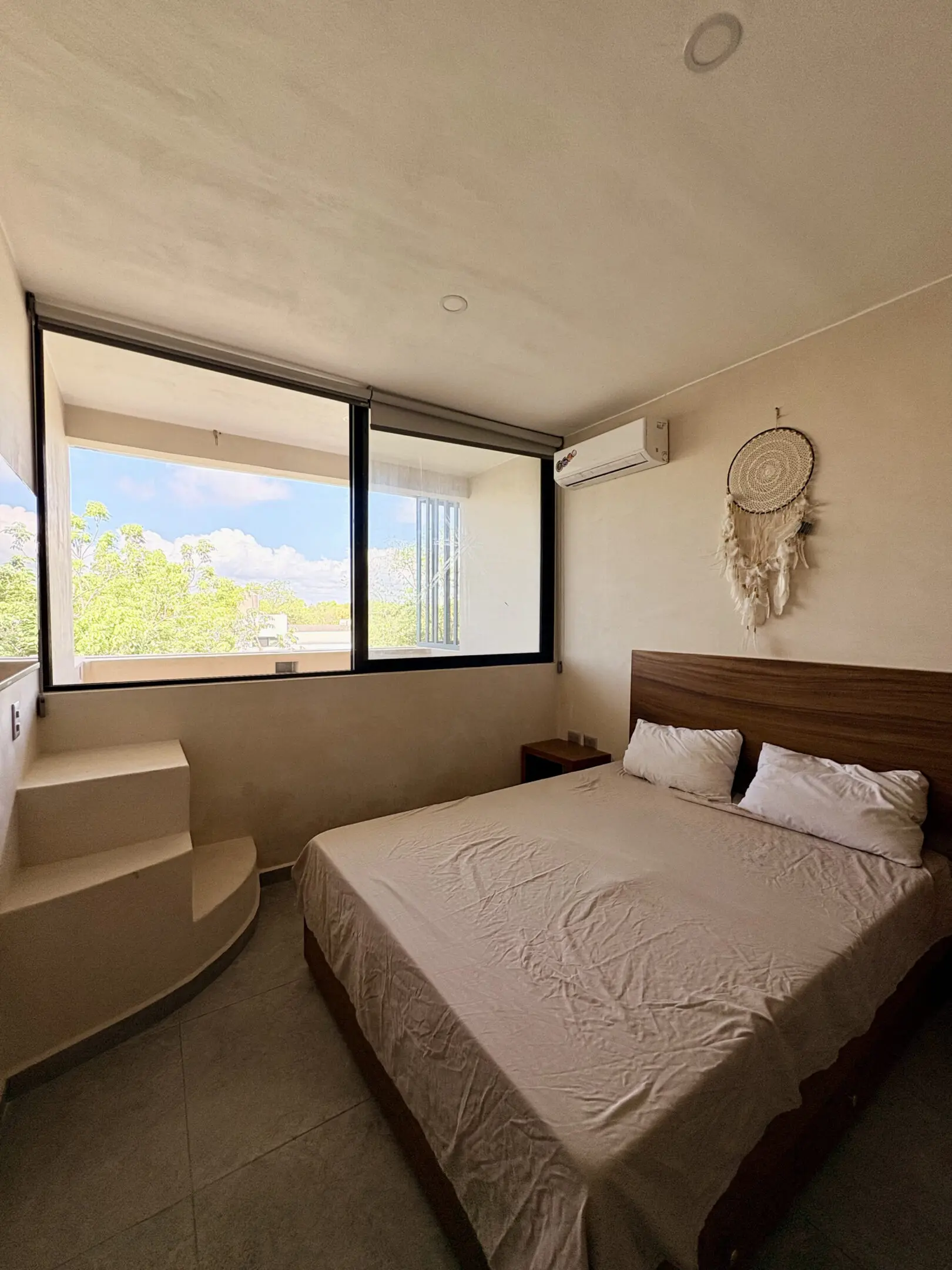 Minimalist bedroom with large window and dreamcatcher