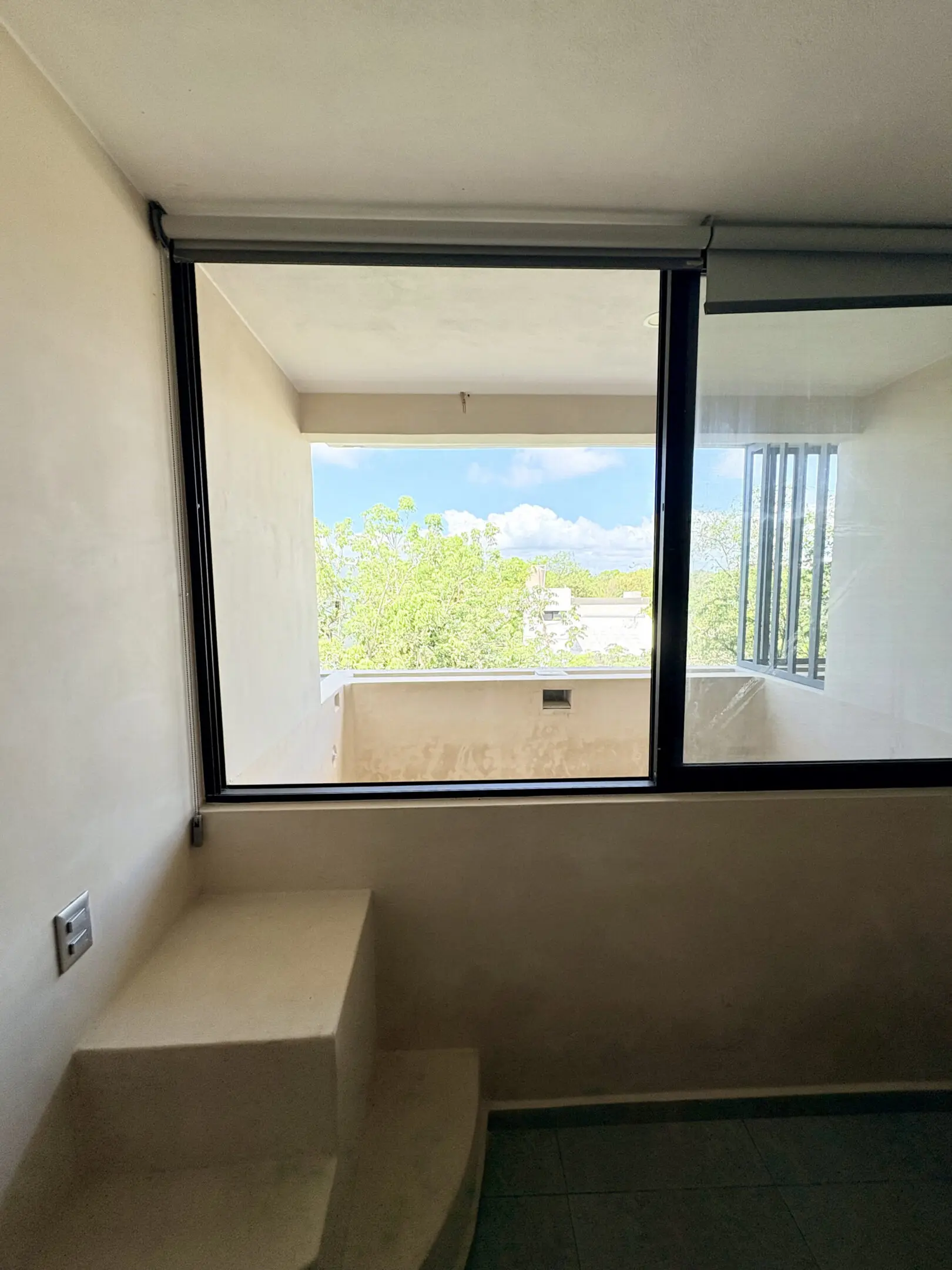 Interior window overlooking balcony with trees