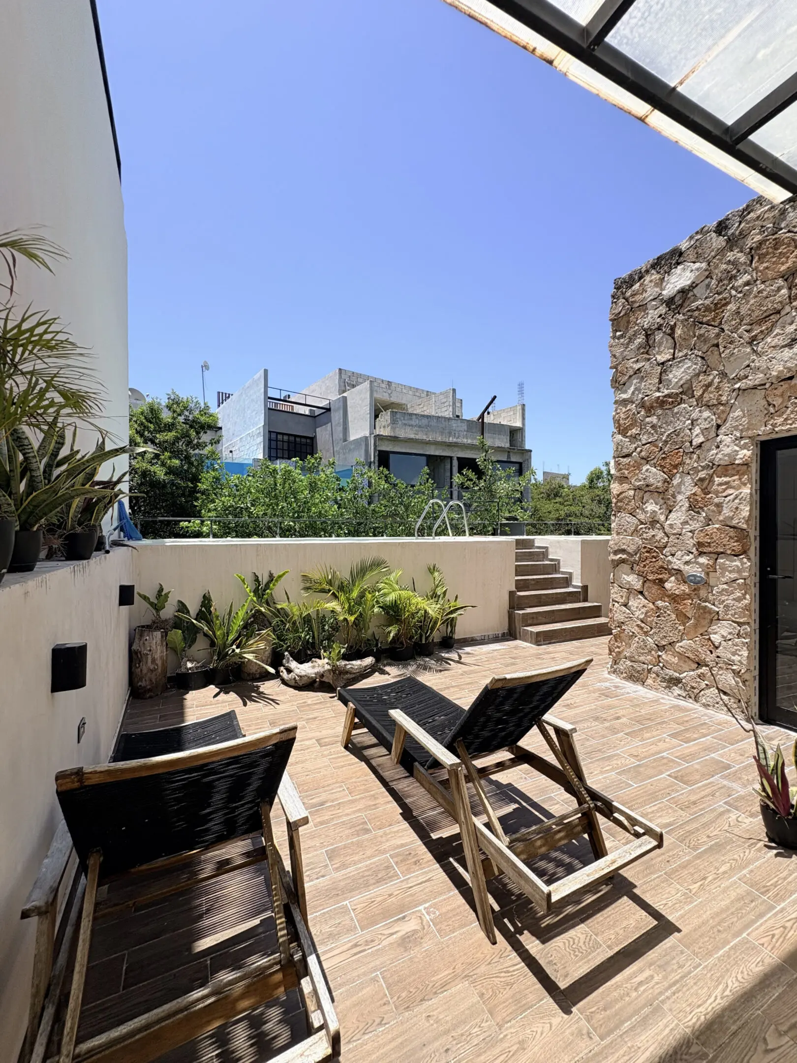 Sunlit terrace with two wooden lounge chairs
