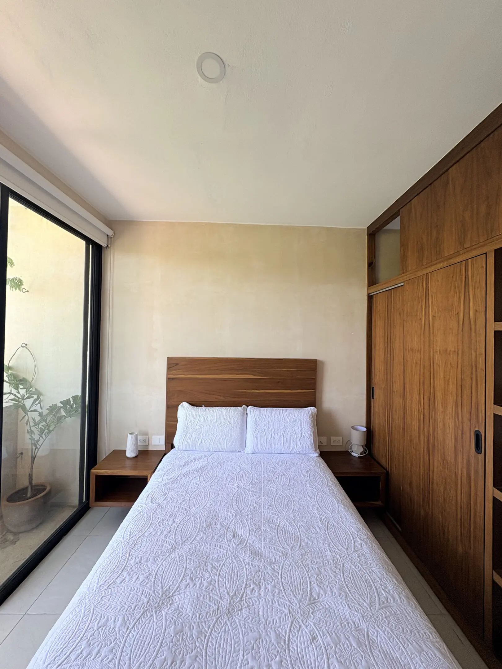Minimalist bedroom with white bed and wooden wardrobe