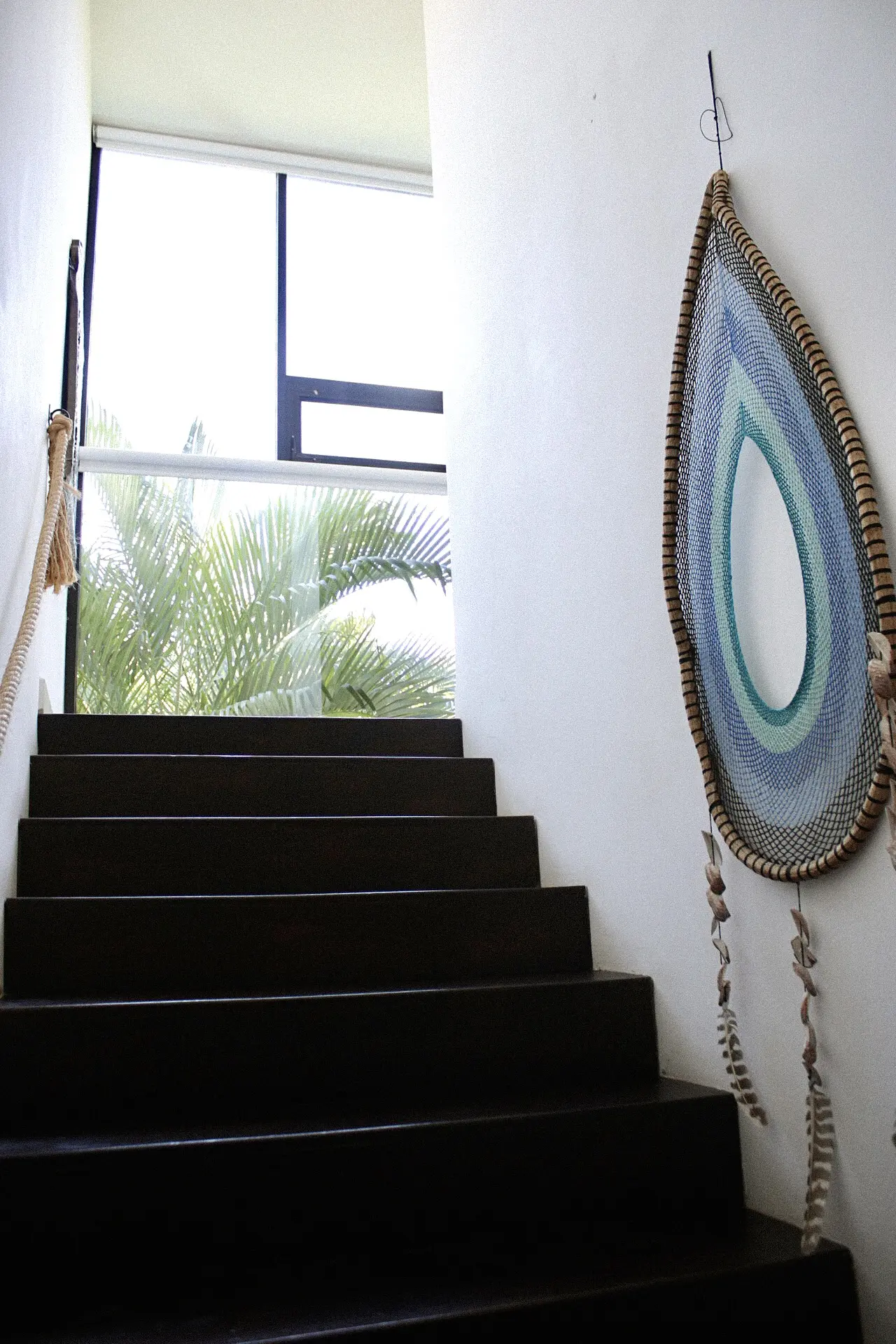 Dark stairs with woven teardrop wall mirror