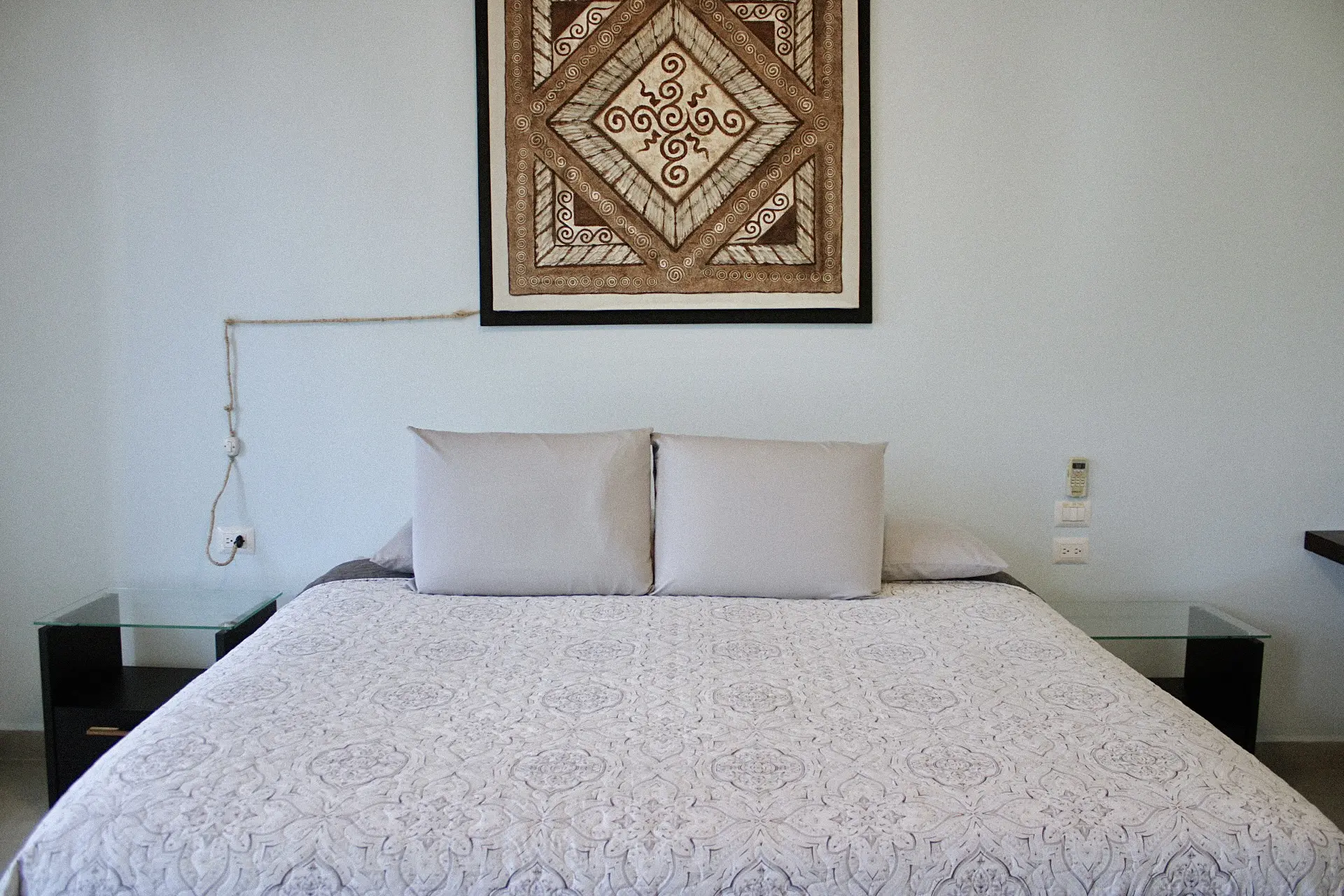 Minimal bedroom with patterned bedspread and artwork