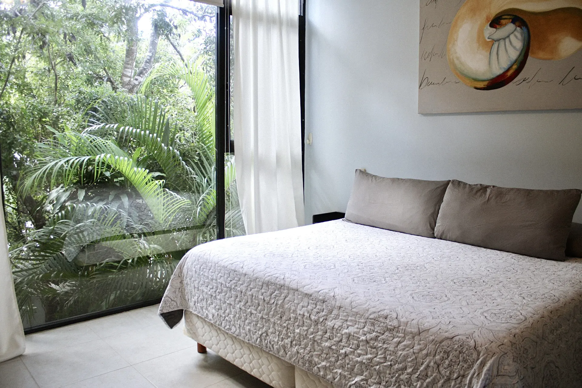 Bedroom with large window and lush greenery