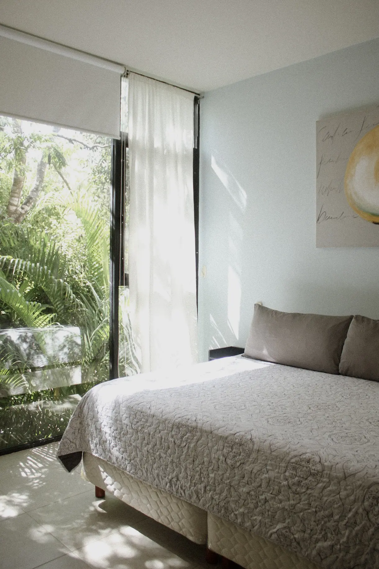 Sunlit bedroom with large window and greenery
