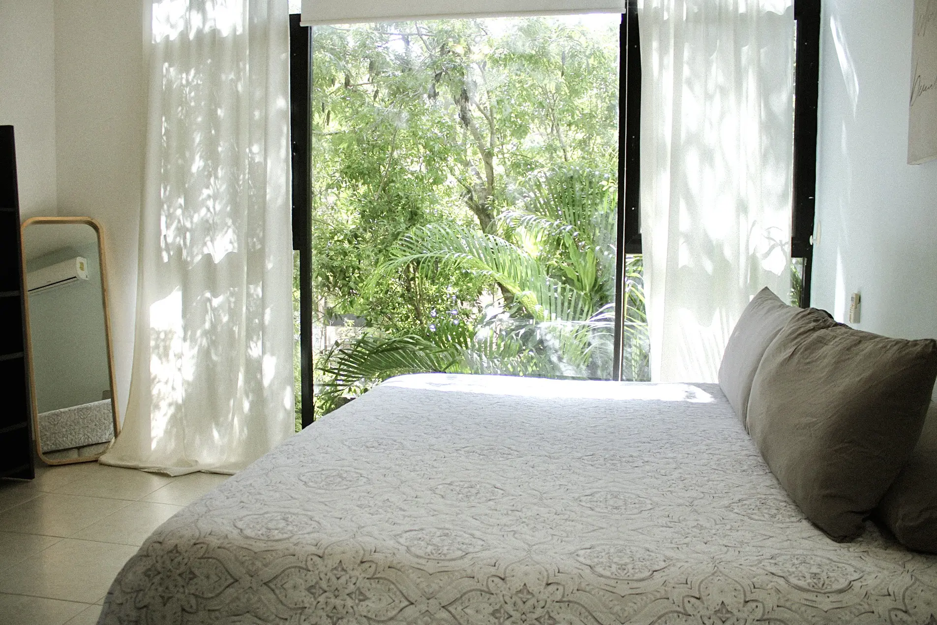 Sunlit bedroom with bed and leafy view