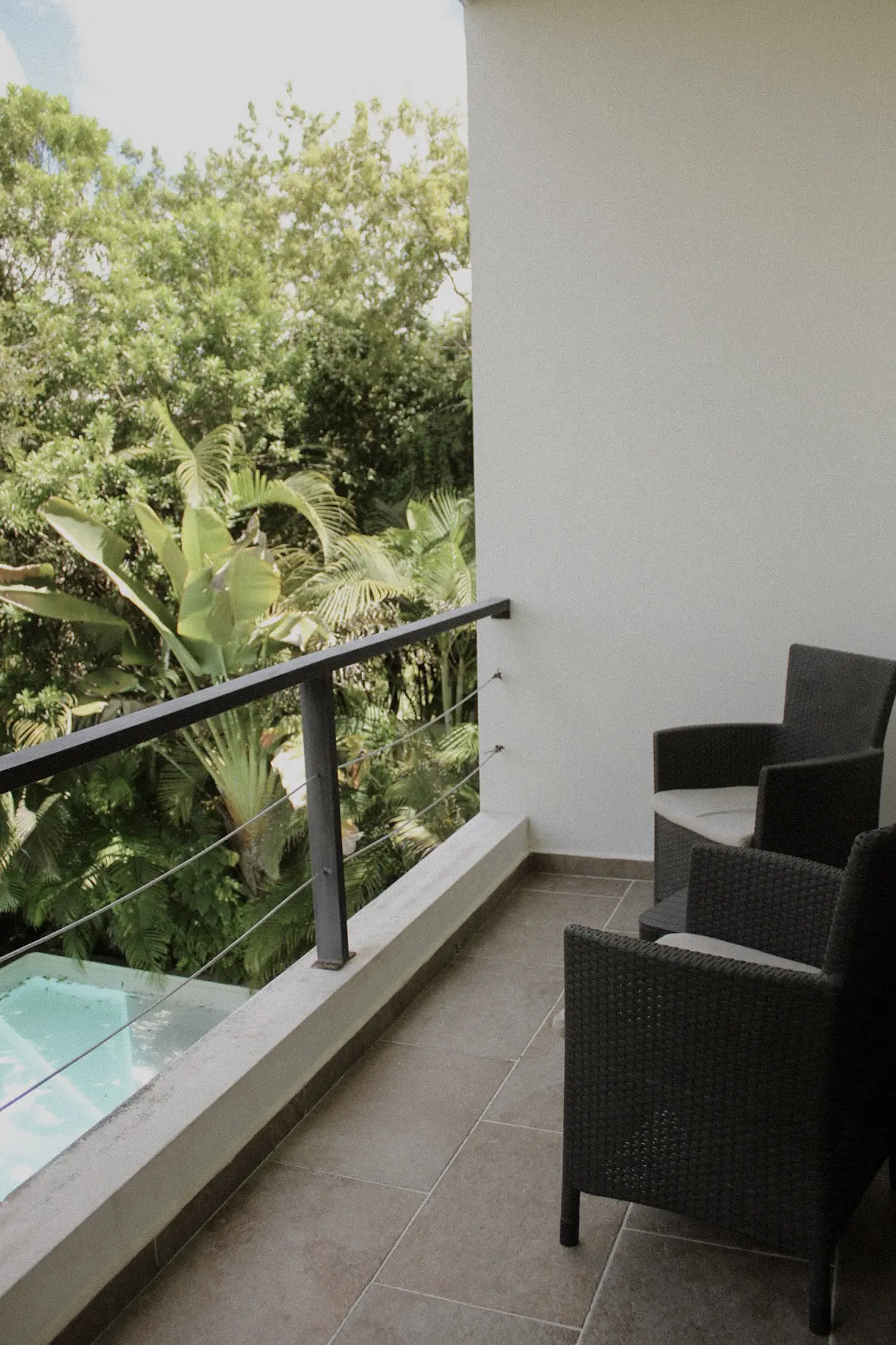 Balcony with two wicker chairs overlooking lush trees